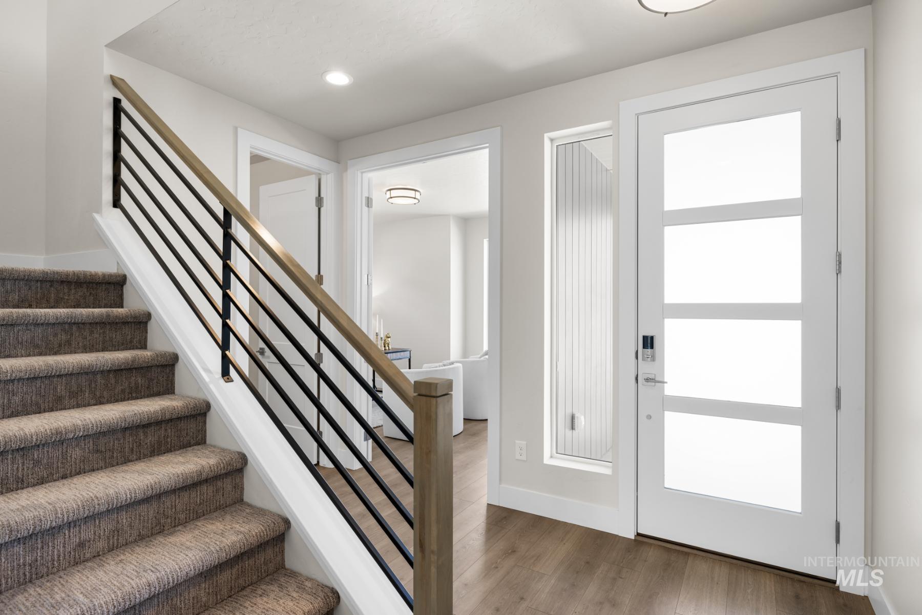 Entryway with wood finished floors, recessed lighting, and stairway