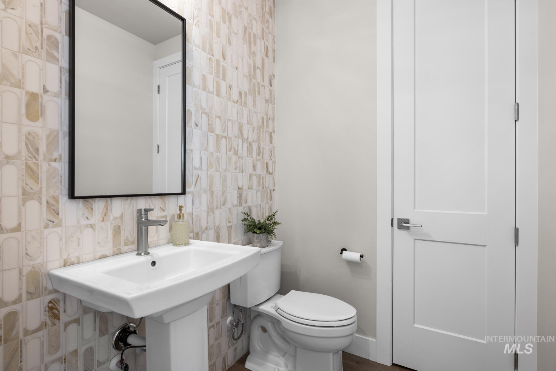 Half bathroom featuring tile walls and backsplash