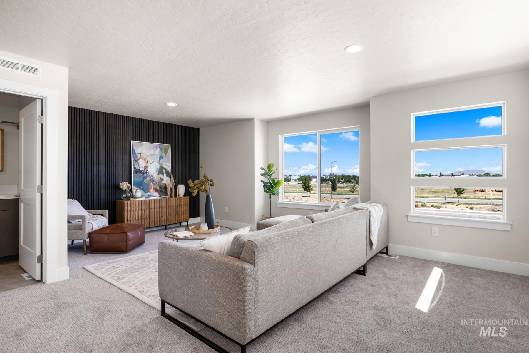 Carpeted living area featuring a textured ceiling, recessed lighting, and an accent wall