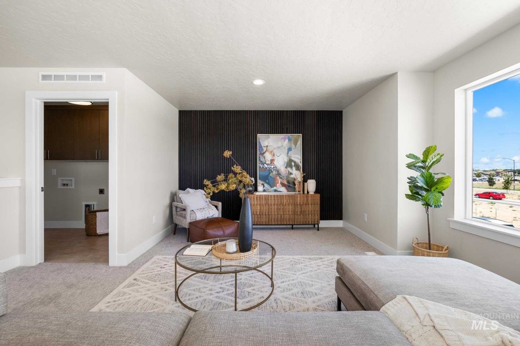 Living area with carpet floors, an accent wall, and a textured ceiling
