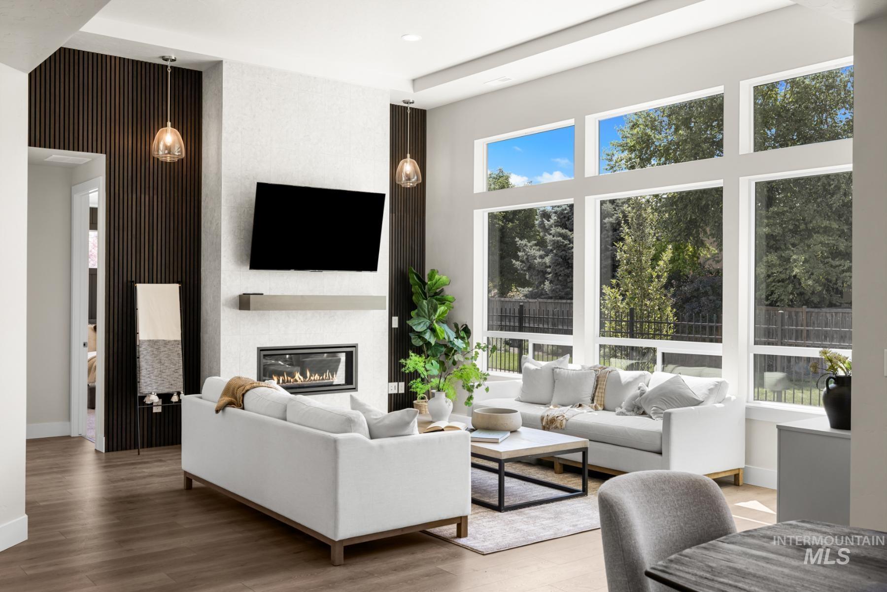 Living room with a large fireplace, wood finished floors, and recessed lighting