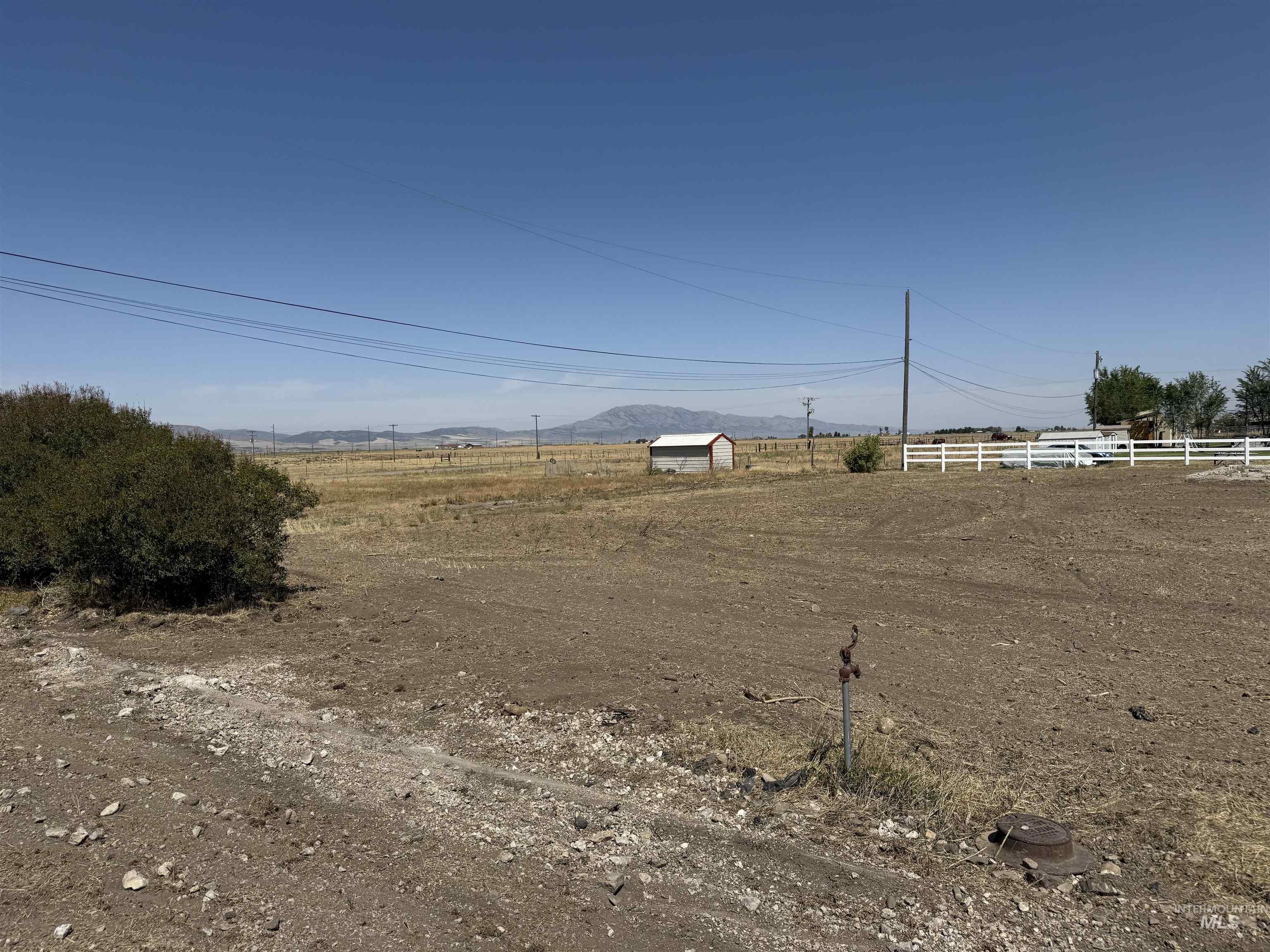 View of yard with a rural view, an outdoor structure, and a mountain view