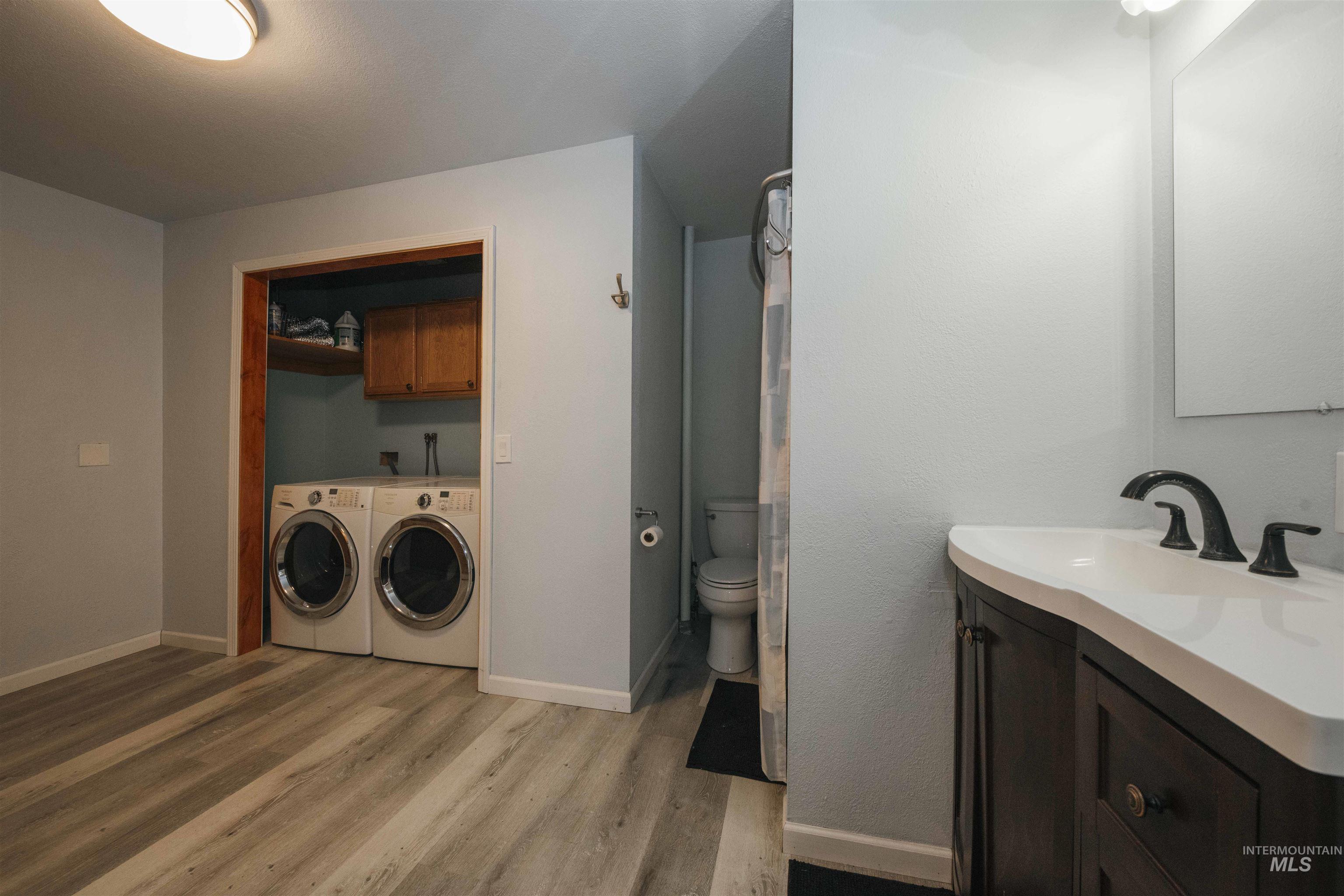 Bathroom featuring washer and dryer, wood finished floors, and vanity