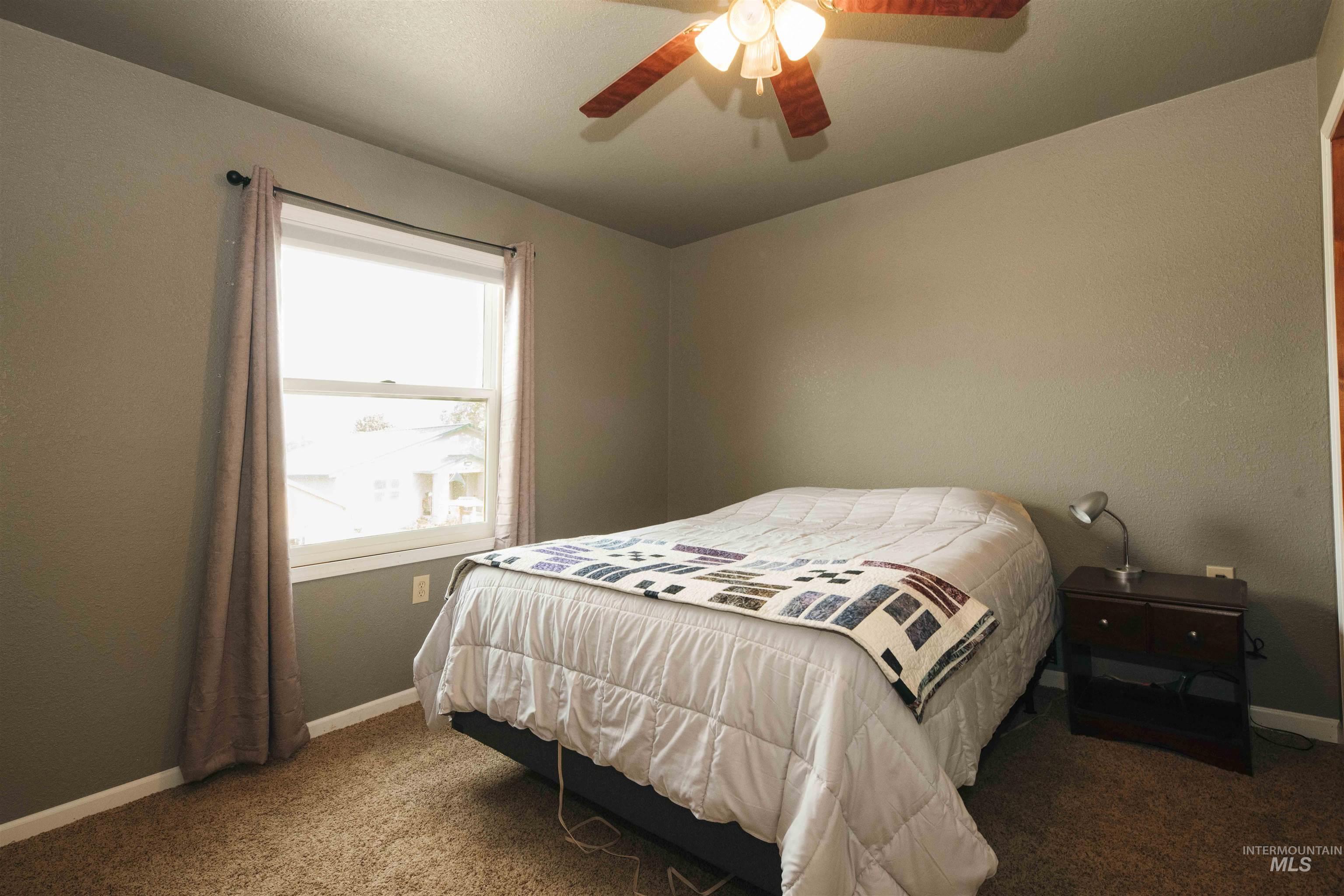 Carpeted bedroom featuring baseboards and a ceiling fan