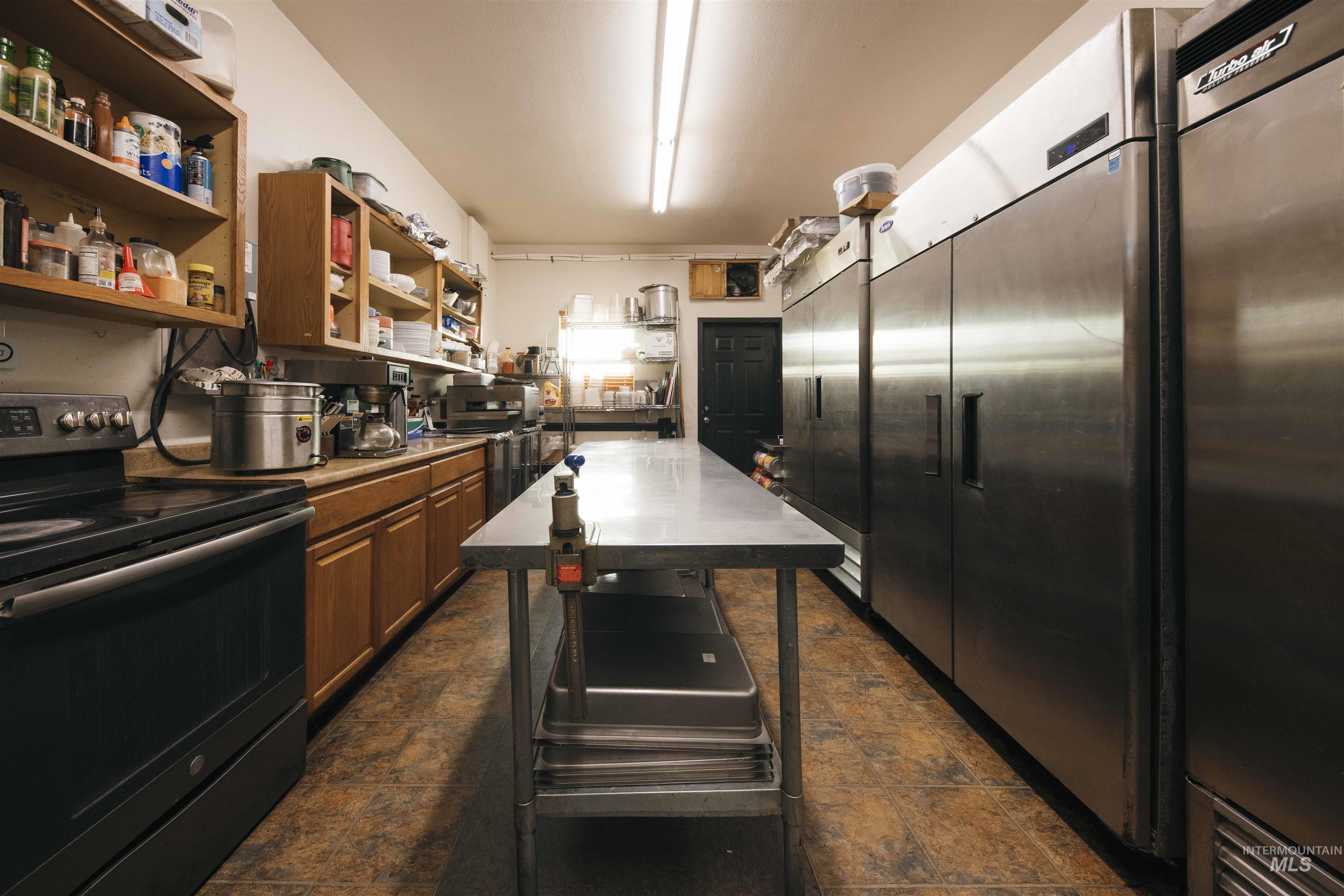 Kitchen featuring electric stove, open shelves, fridge, built in fridge, and brown cabinetry