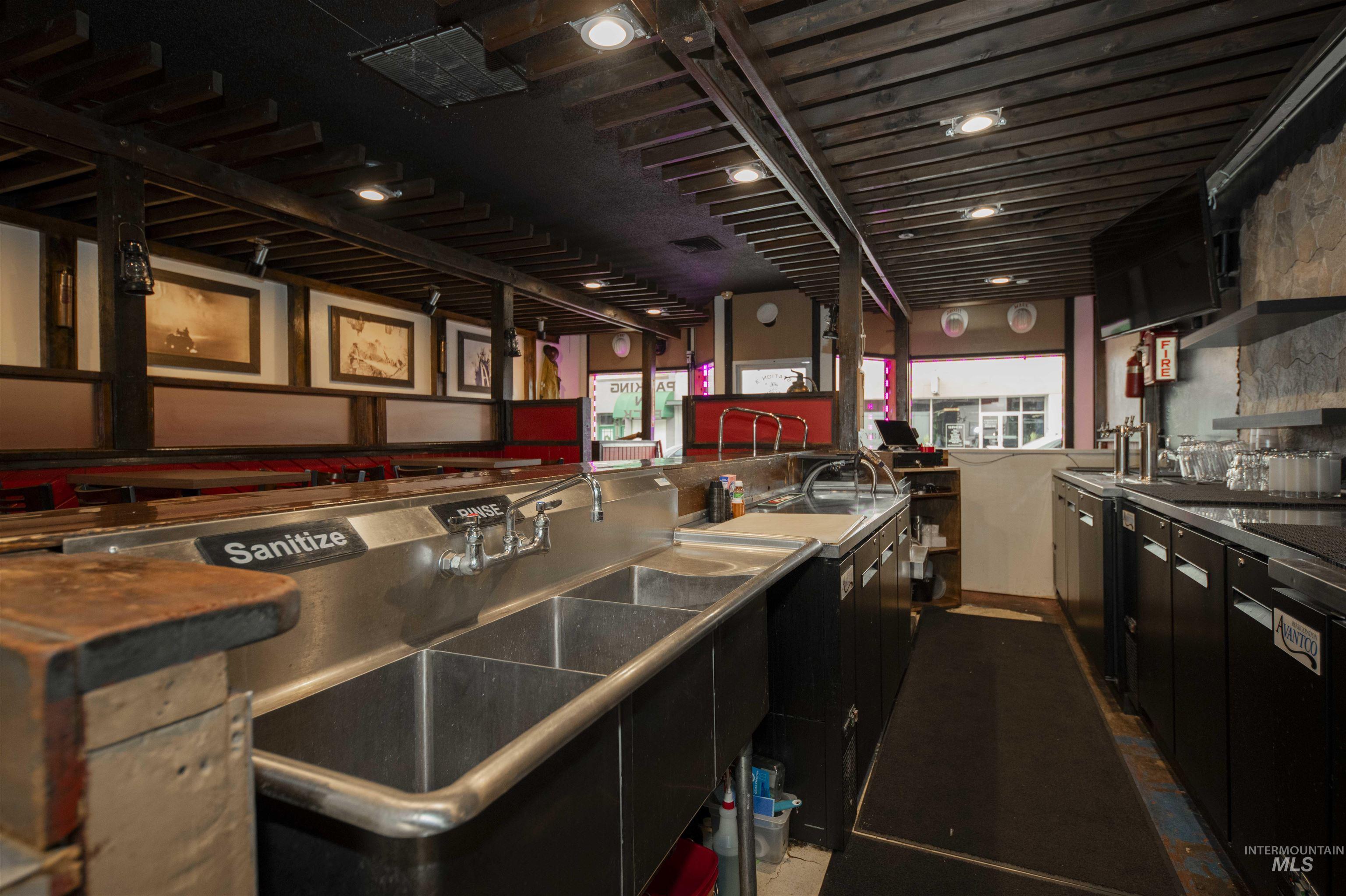 Behind bar with a sink and dark cabinetry
