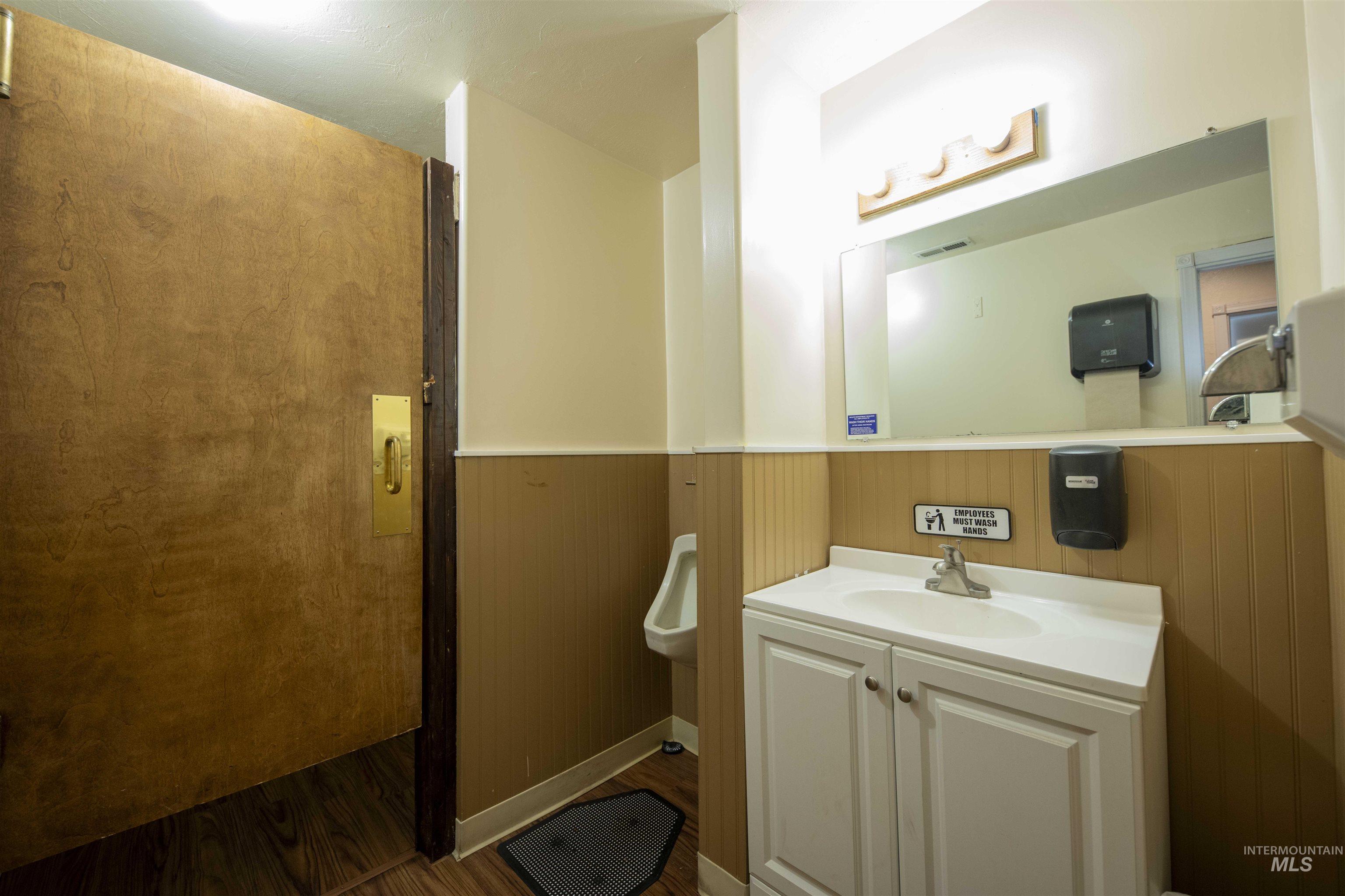 Bathroom featuring wood finished floors, vanity, and a wainscoted wall