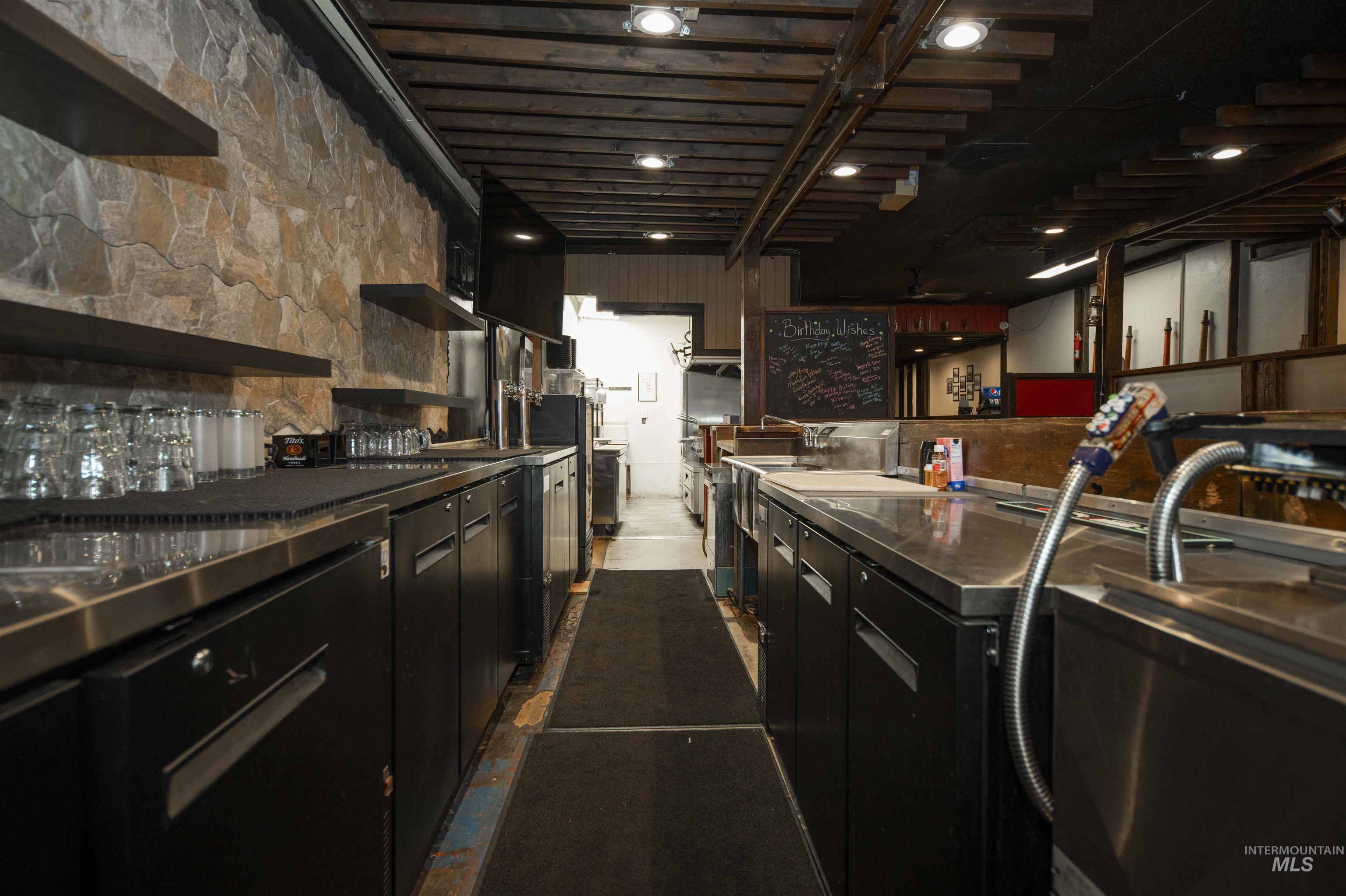 Behind the bar featuring dark cabinetry and open shelves