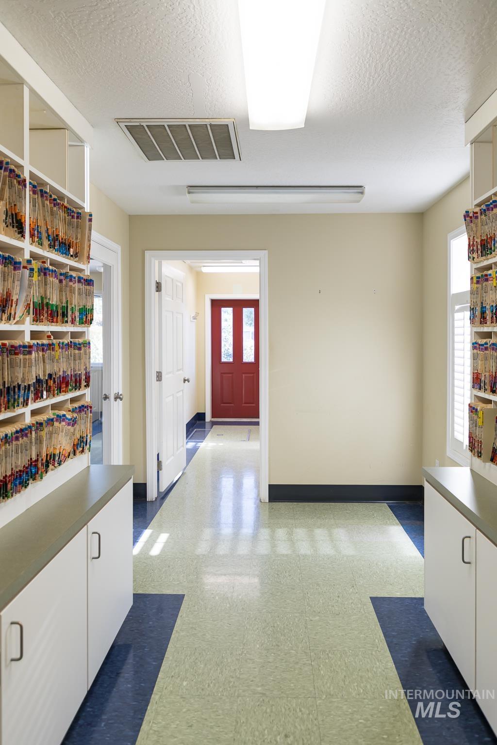 Hallway with light flooring, plenty of natural light, and a textured ceiling
