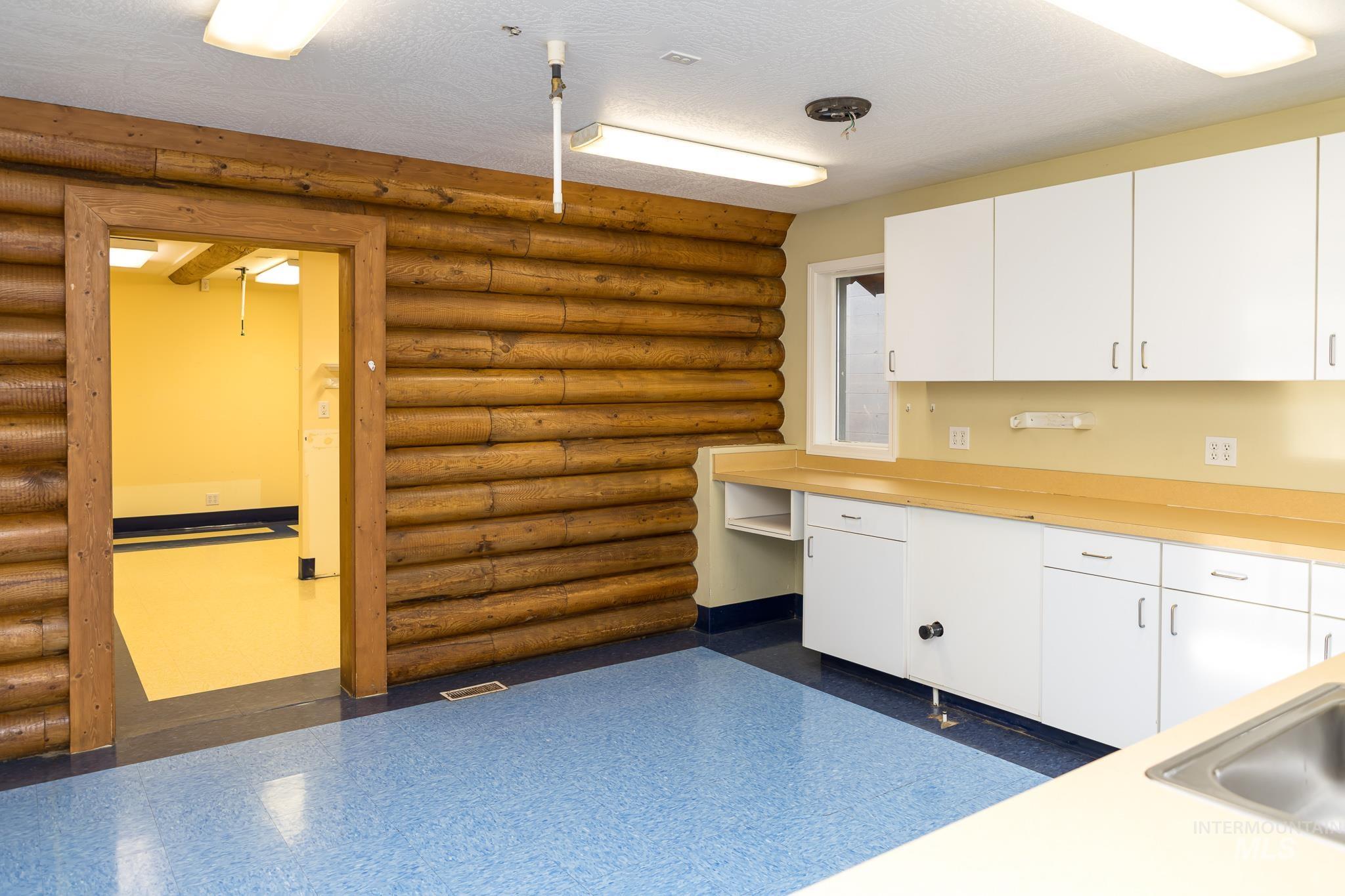 Kitchen featuring light countertops, white cabinets, log walls, built in study area, and a textured ceiling