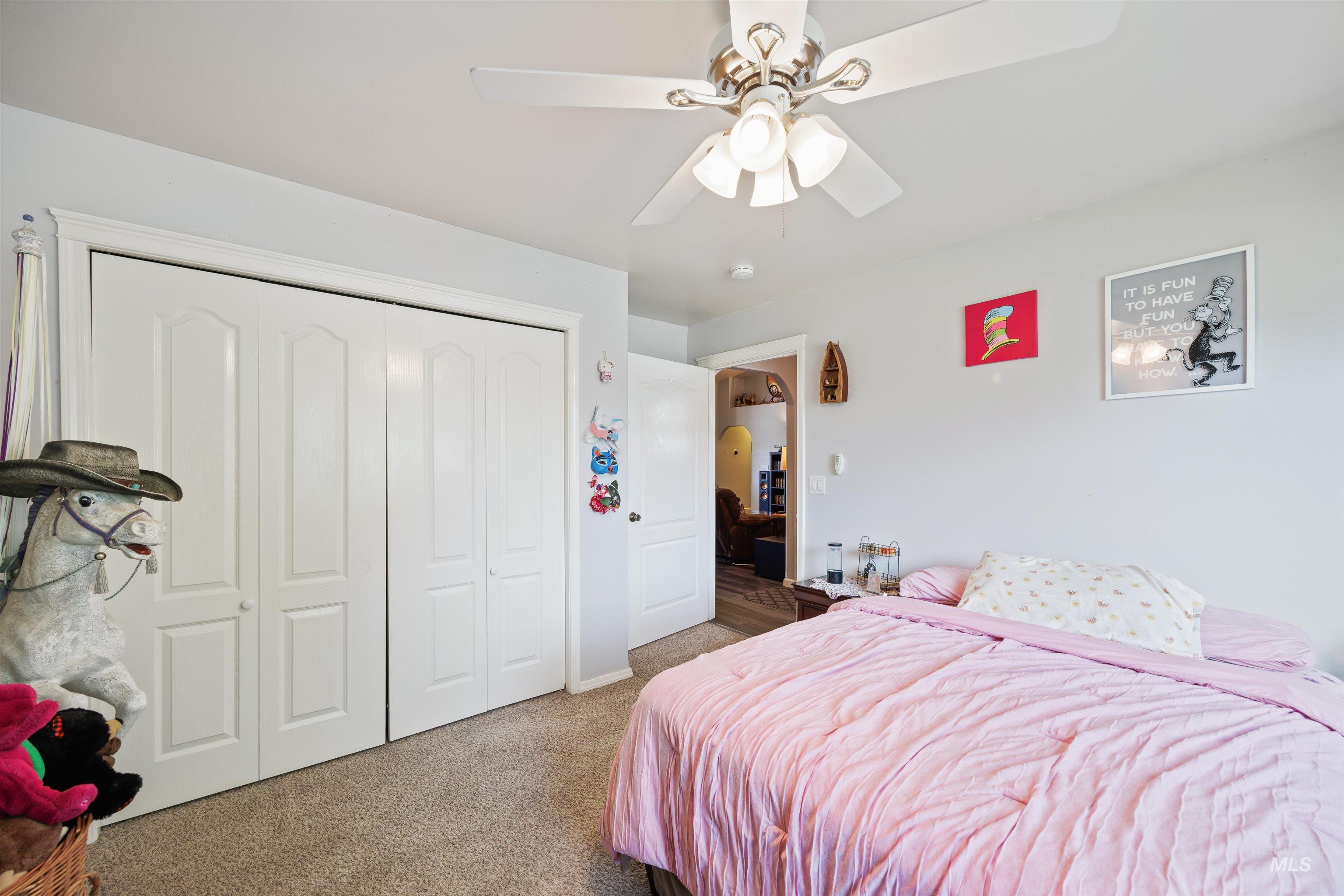 Bedroom featuring carpet flooring, arched walkways, a closet, and a ceiling fan