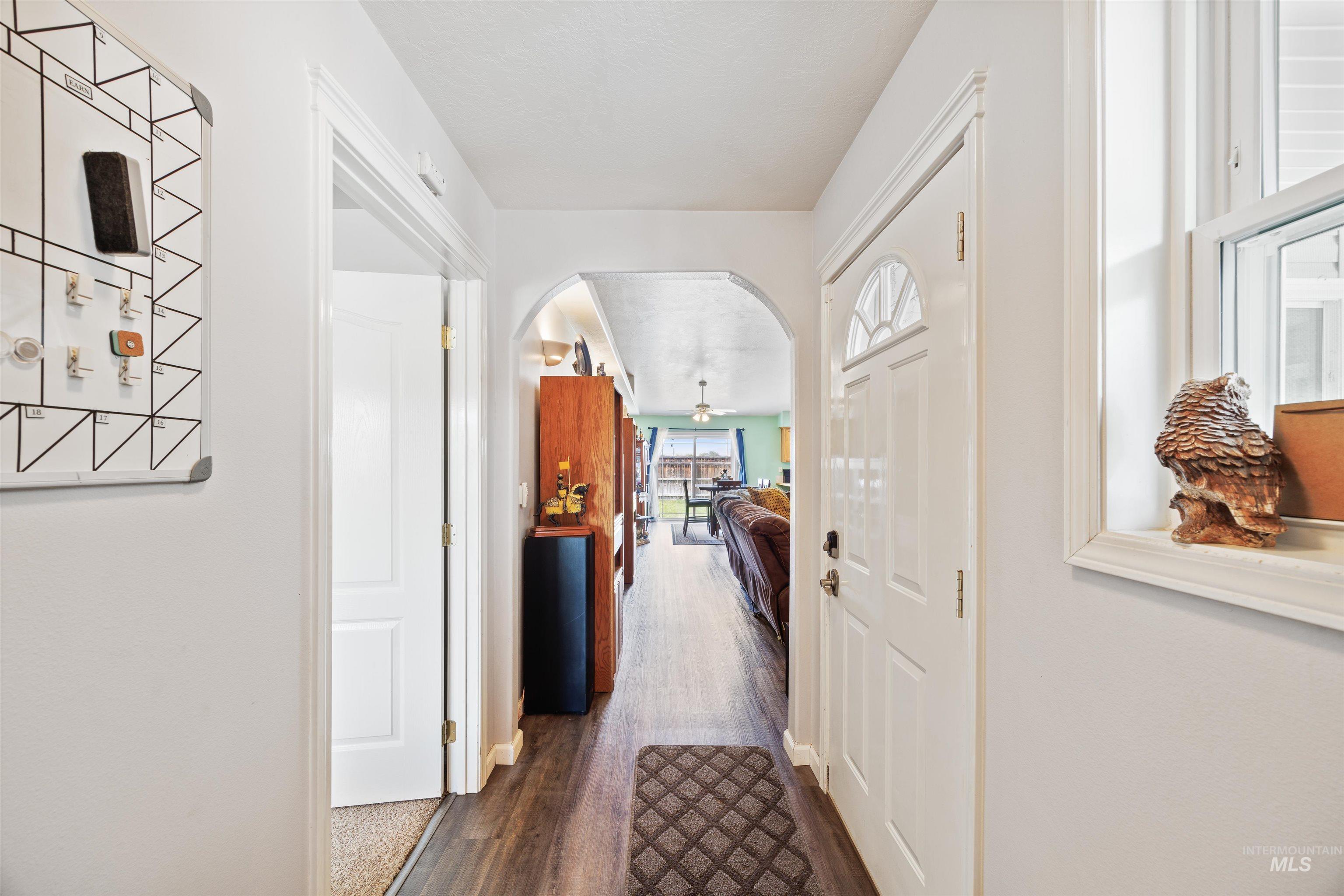Hall featuring arched walkways and dark wood finished floors