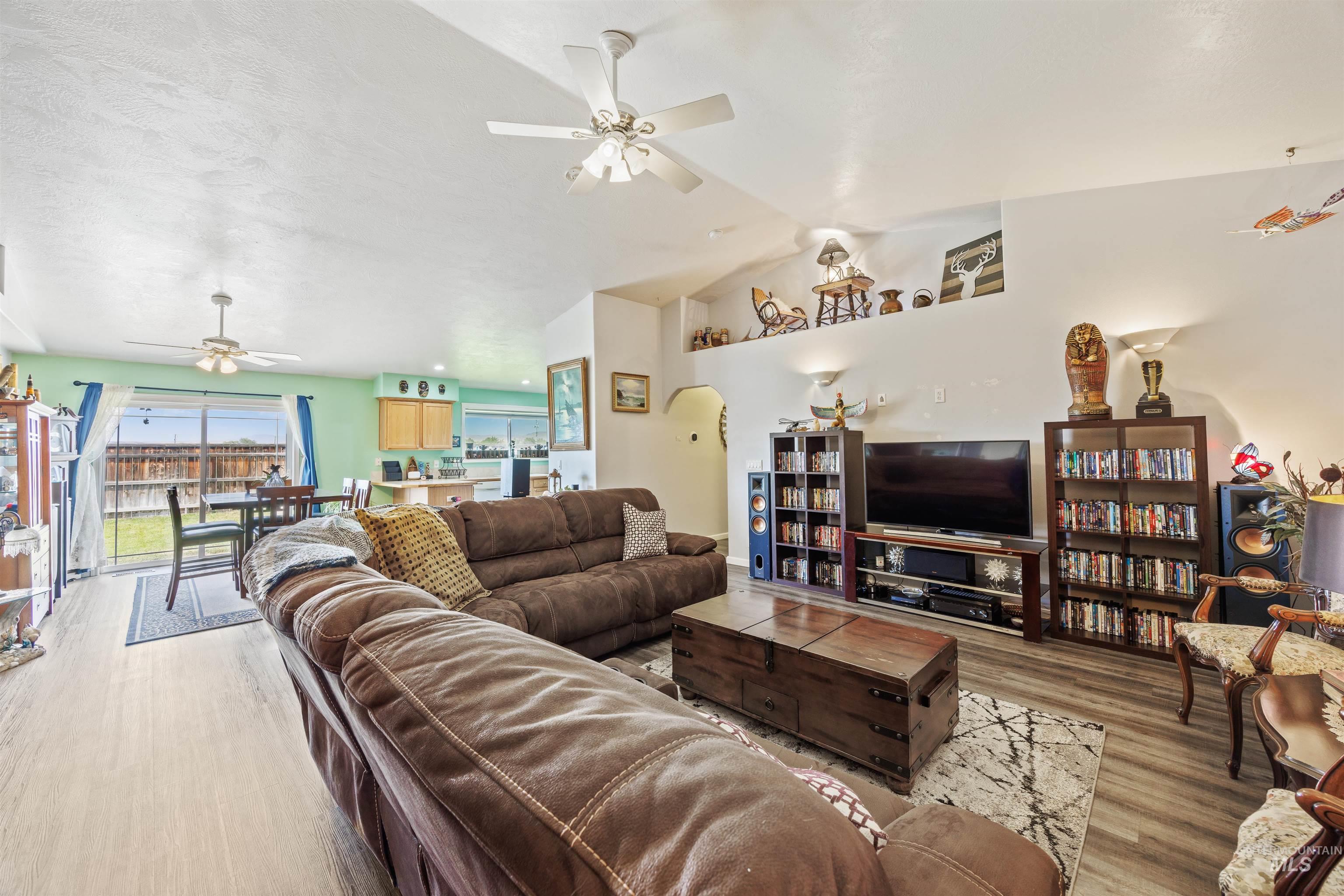 Living room featuring ceiling fan, lofted ceiling, wood finished floors, and arched walkways