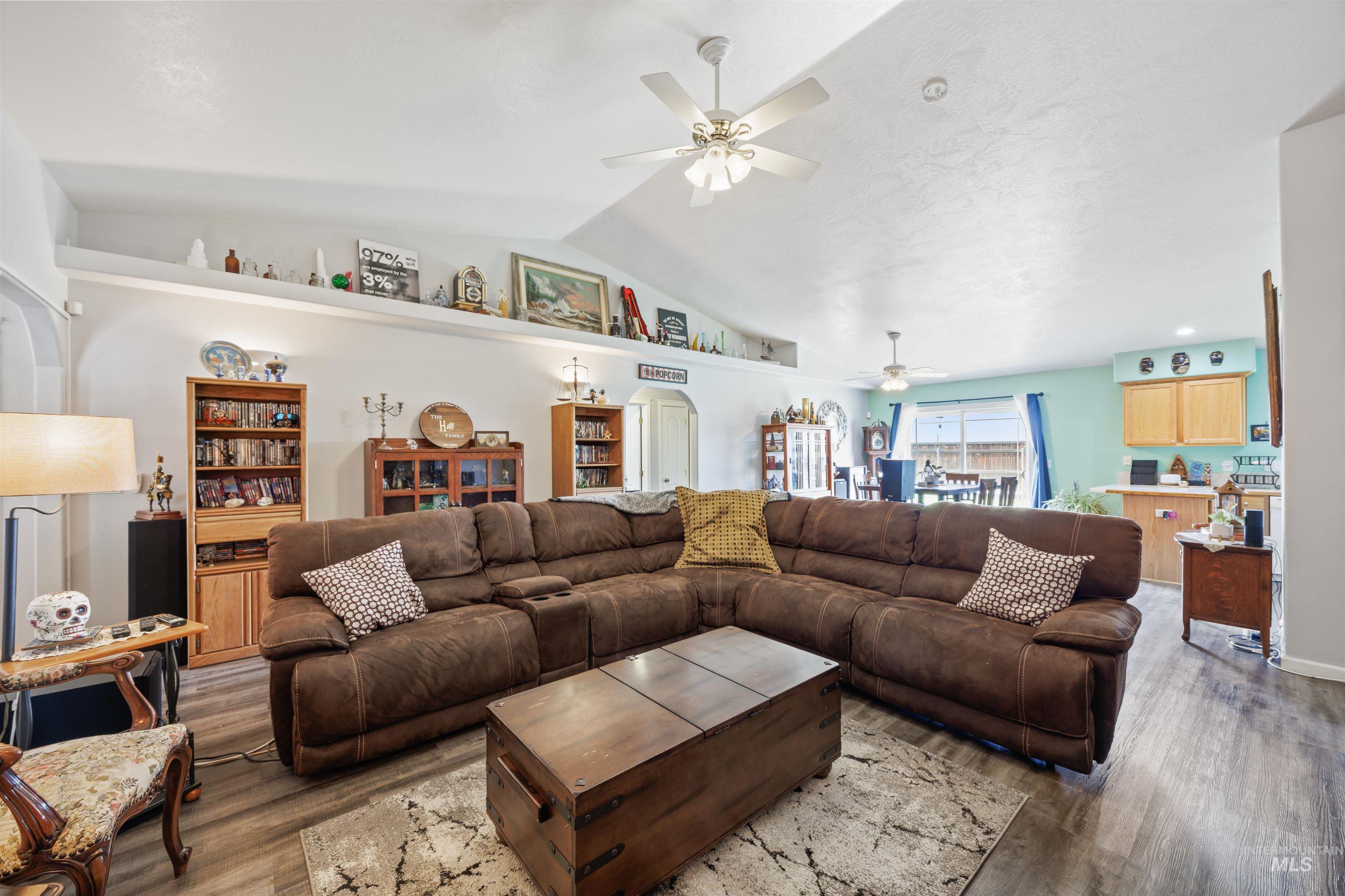 Living room featuring vaulted ceiling, wood finished floors, and ceiling fan