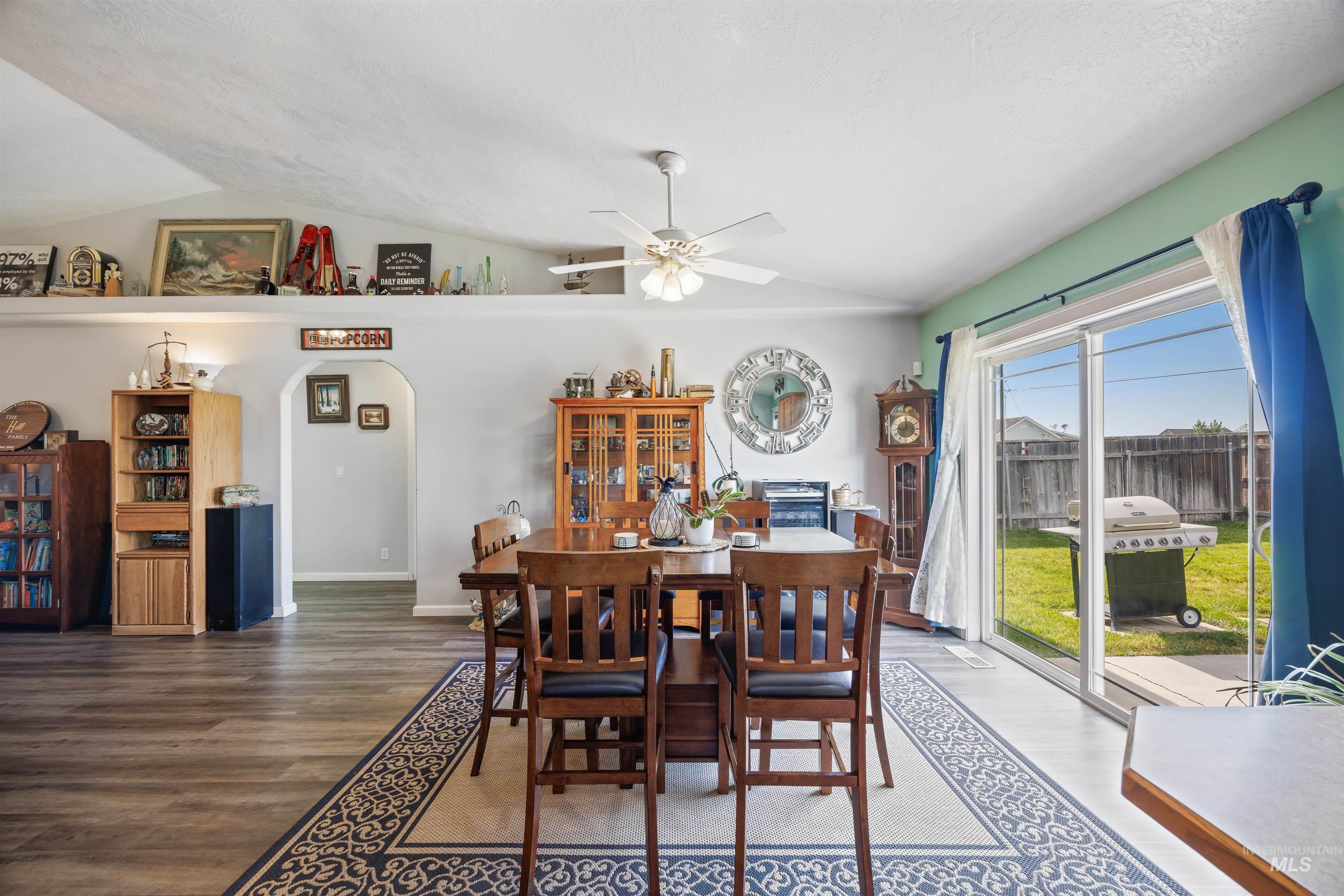 Dining area with arched walkways, vaulted ceiling, wood finished floors, and ceiling fan