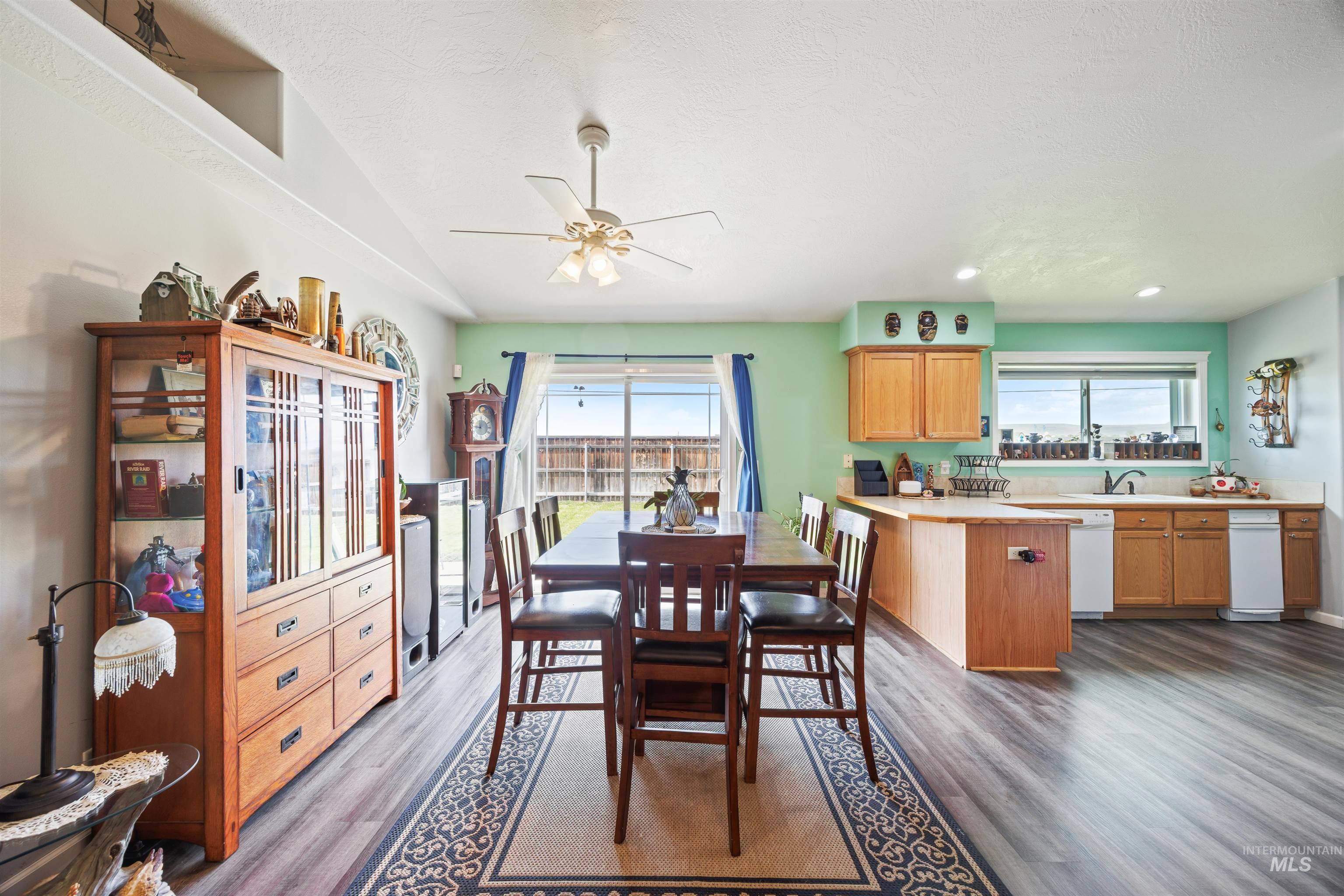 Dining area featuring wood finished floors, a ceiling fan, vaulted ceiling, and a textured ceiling