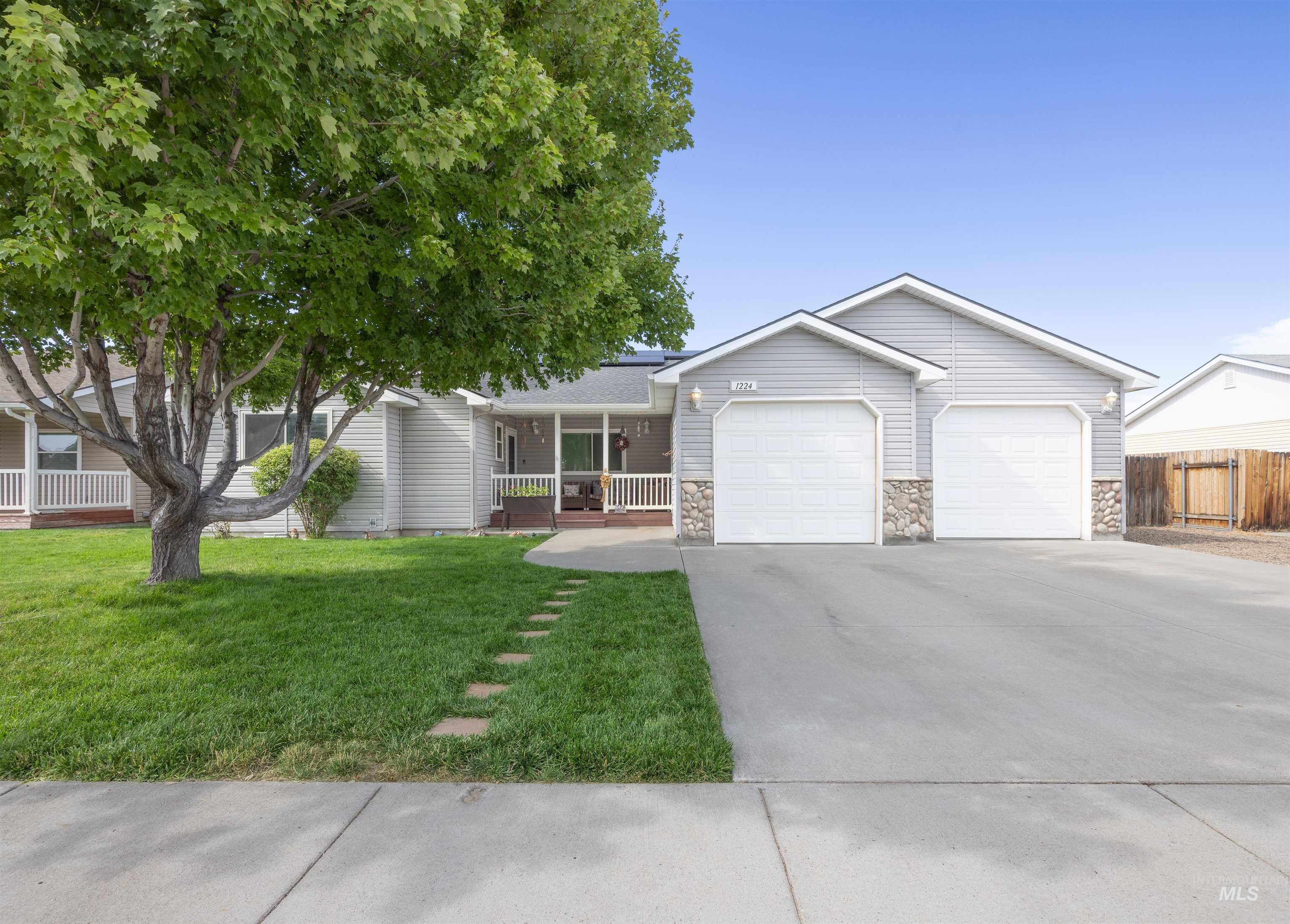 Ranch-style house with a garage, concrete driveway, a porch, and stone siding