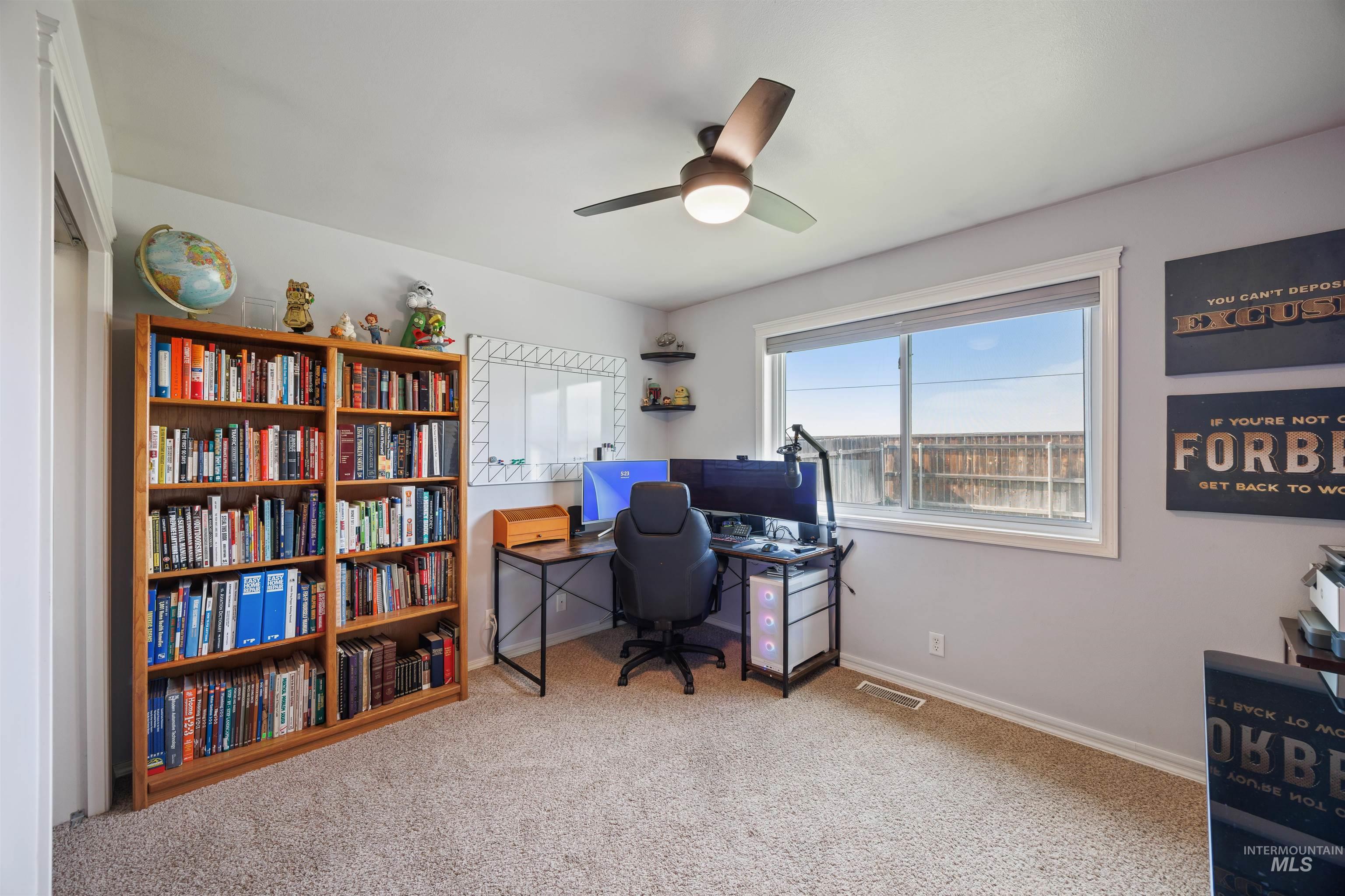 Carpeted office with baseboards and a ceiling fan