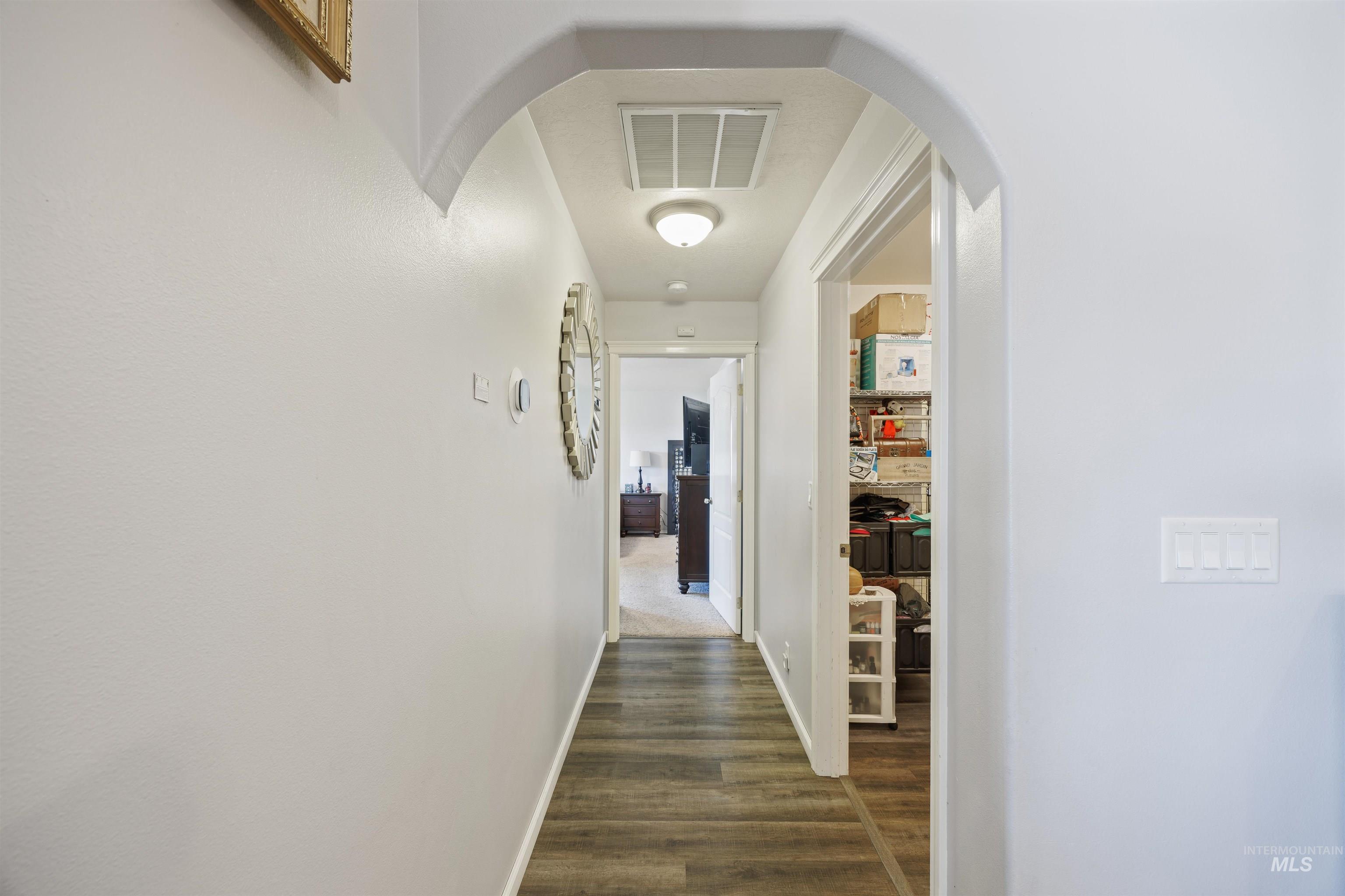 Hall featuring arched walkways and dark wood-style flooring