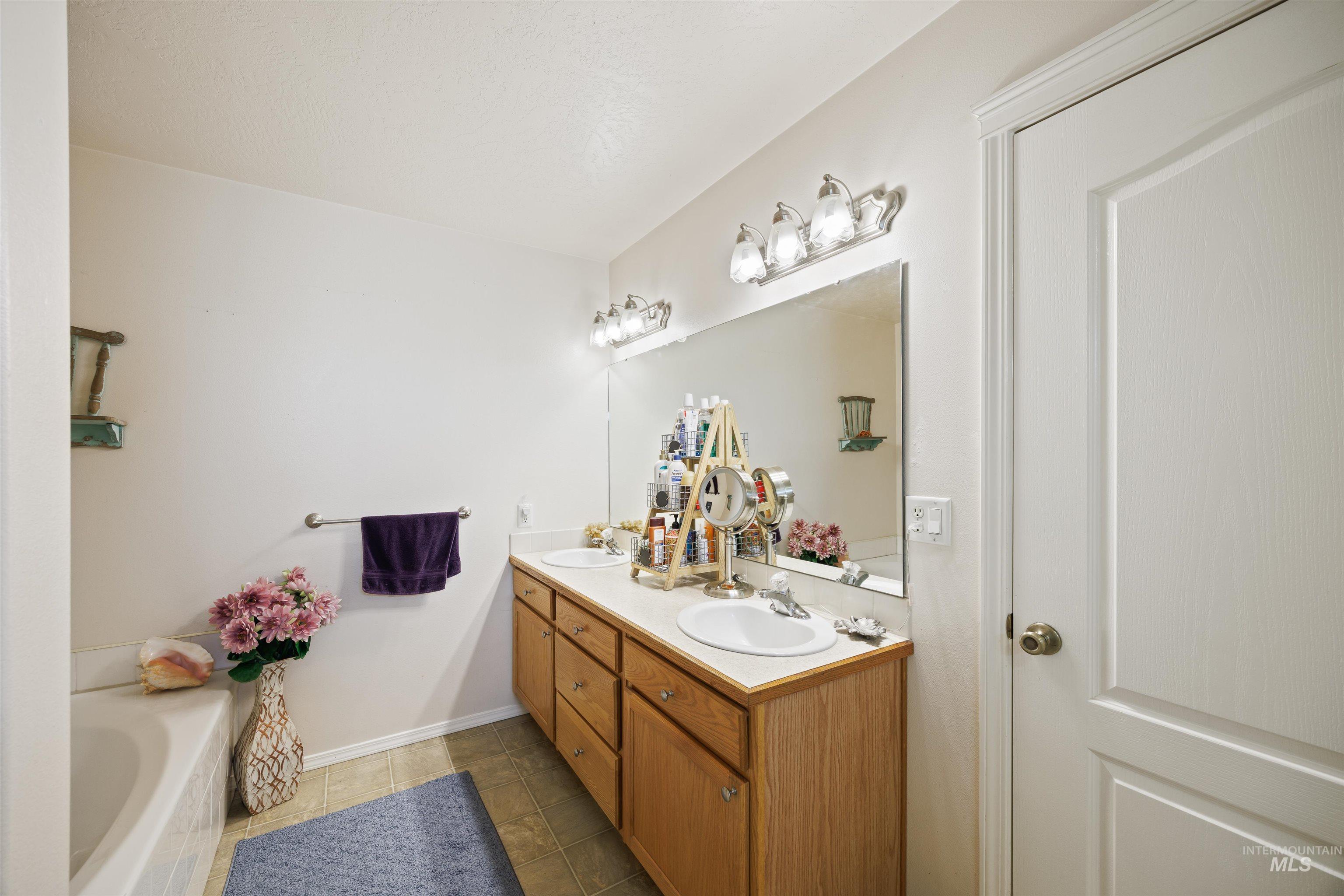 Bathroom featuring double vanity, a bath, and tile patterned floors