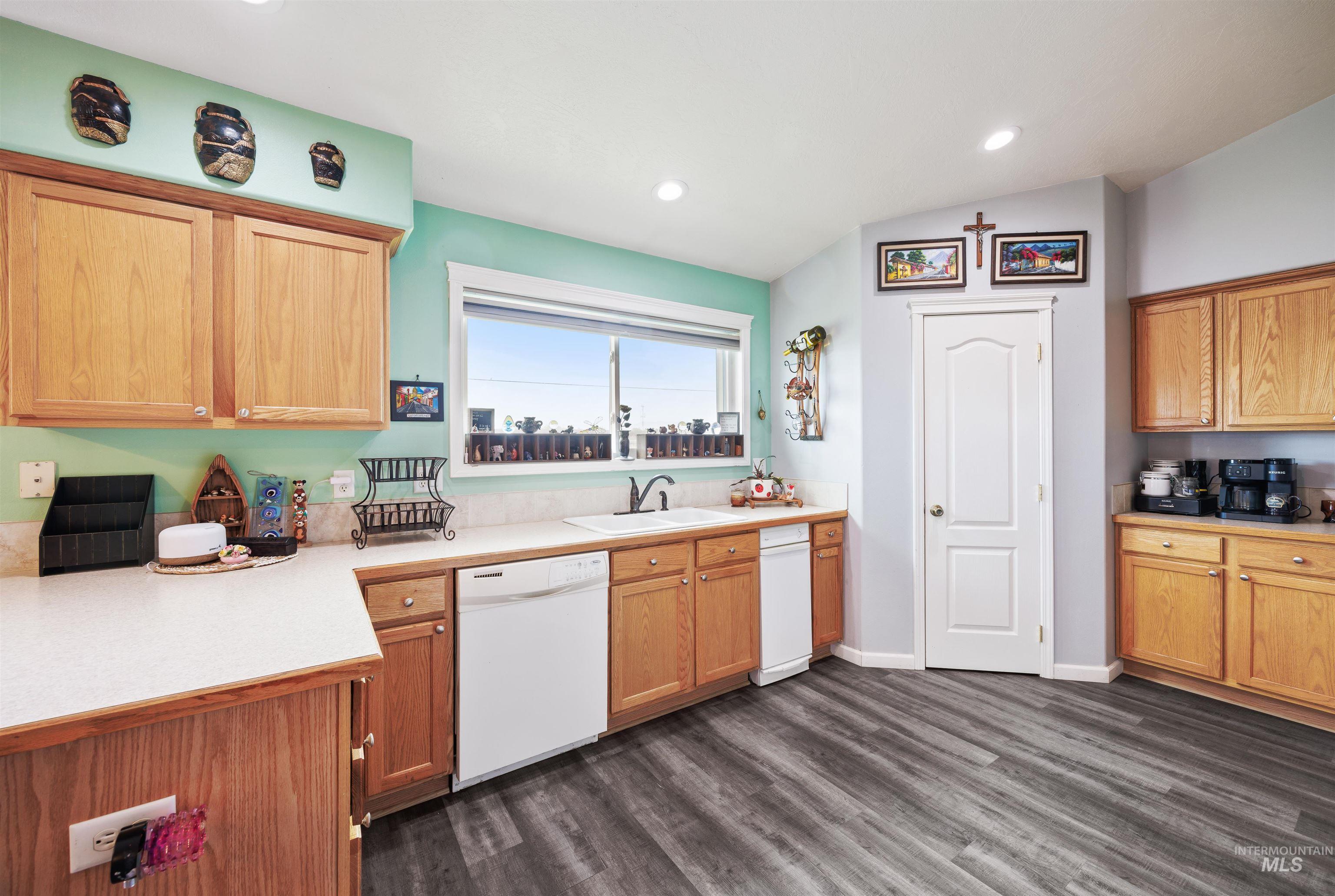 Kitchen with white dishwasher, dark wood-type flooring, light countertops, and recessed lighting