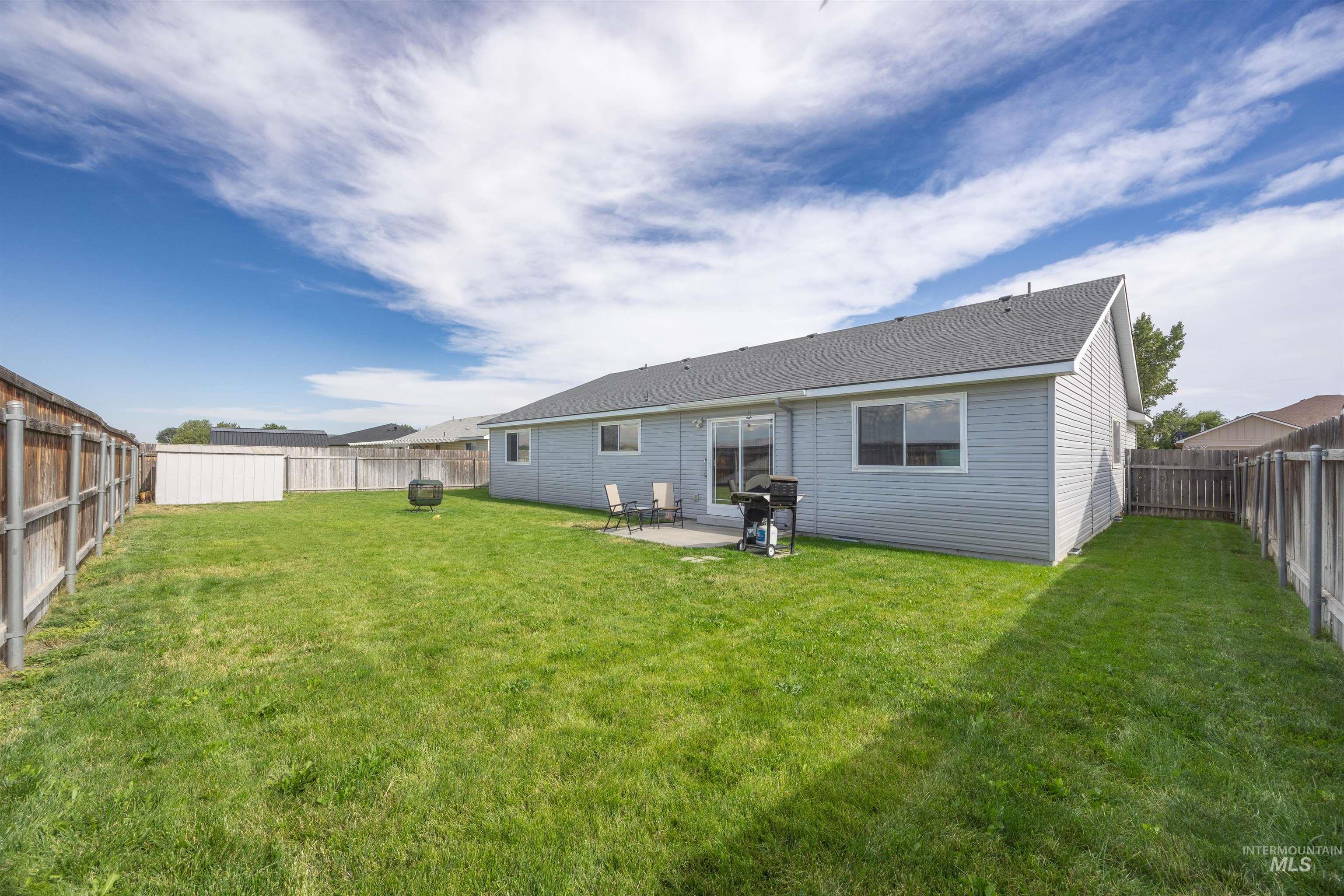 Rear view of property with a fenced backyard, a patio, and roof with shingles