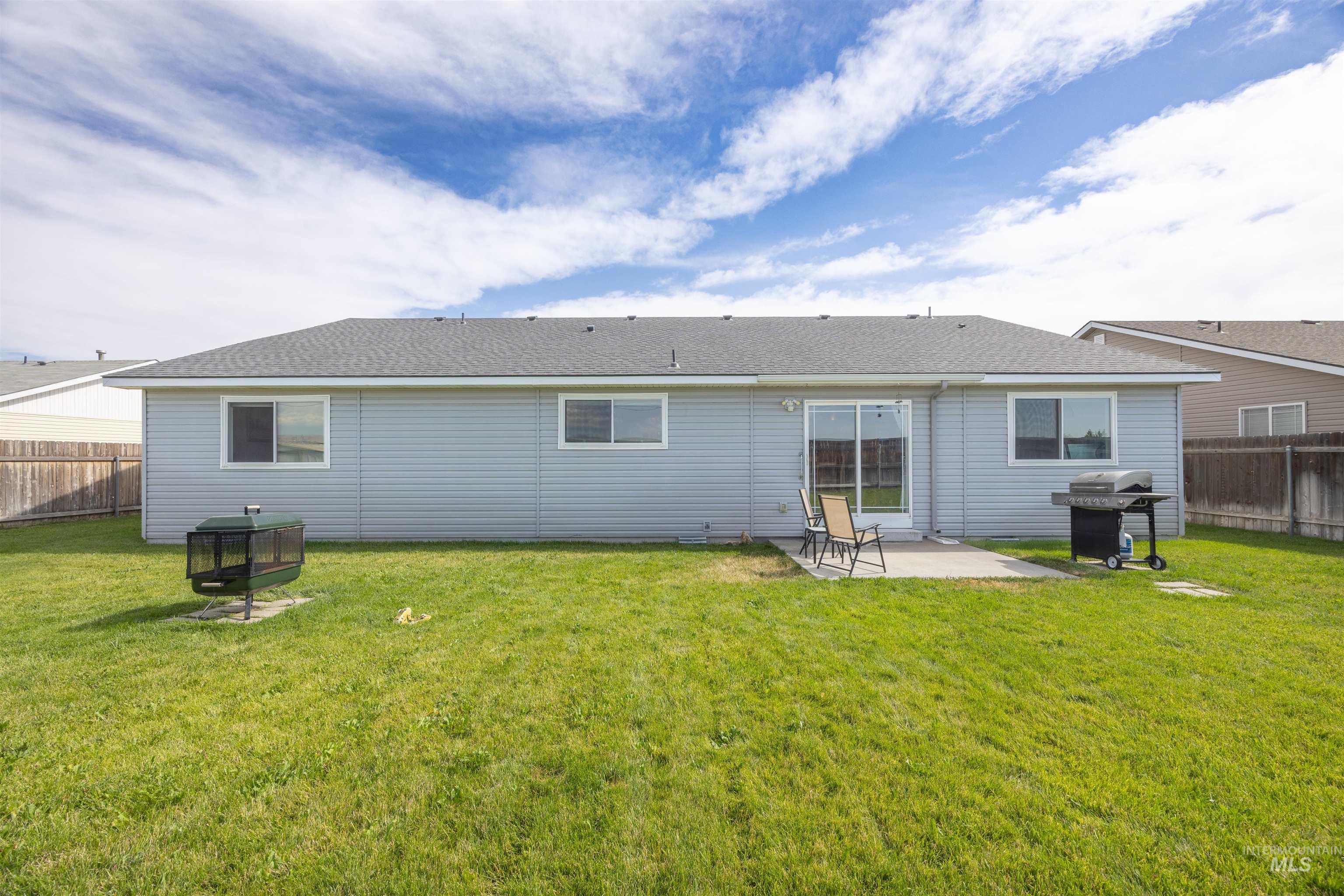 Rear view of property with a fenced backyard, a patio area, and roof with shingles