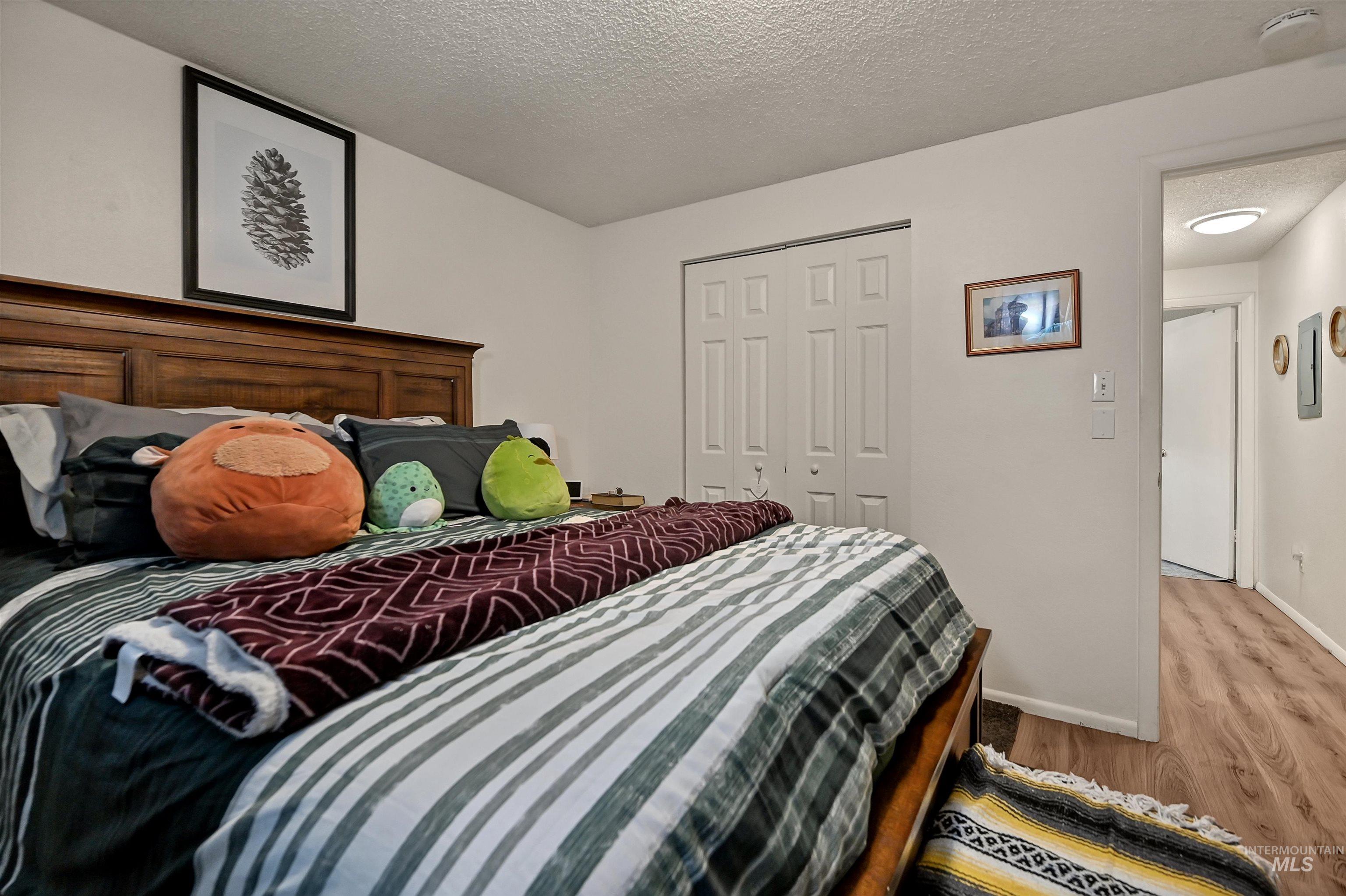 Bedroom with a textured ceiling, light wood-type flooring, and a closet