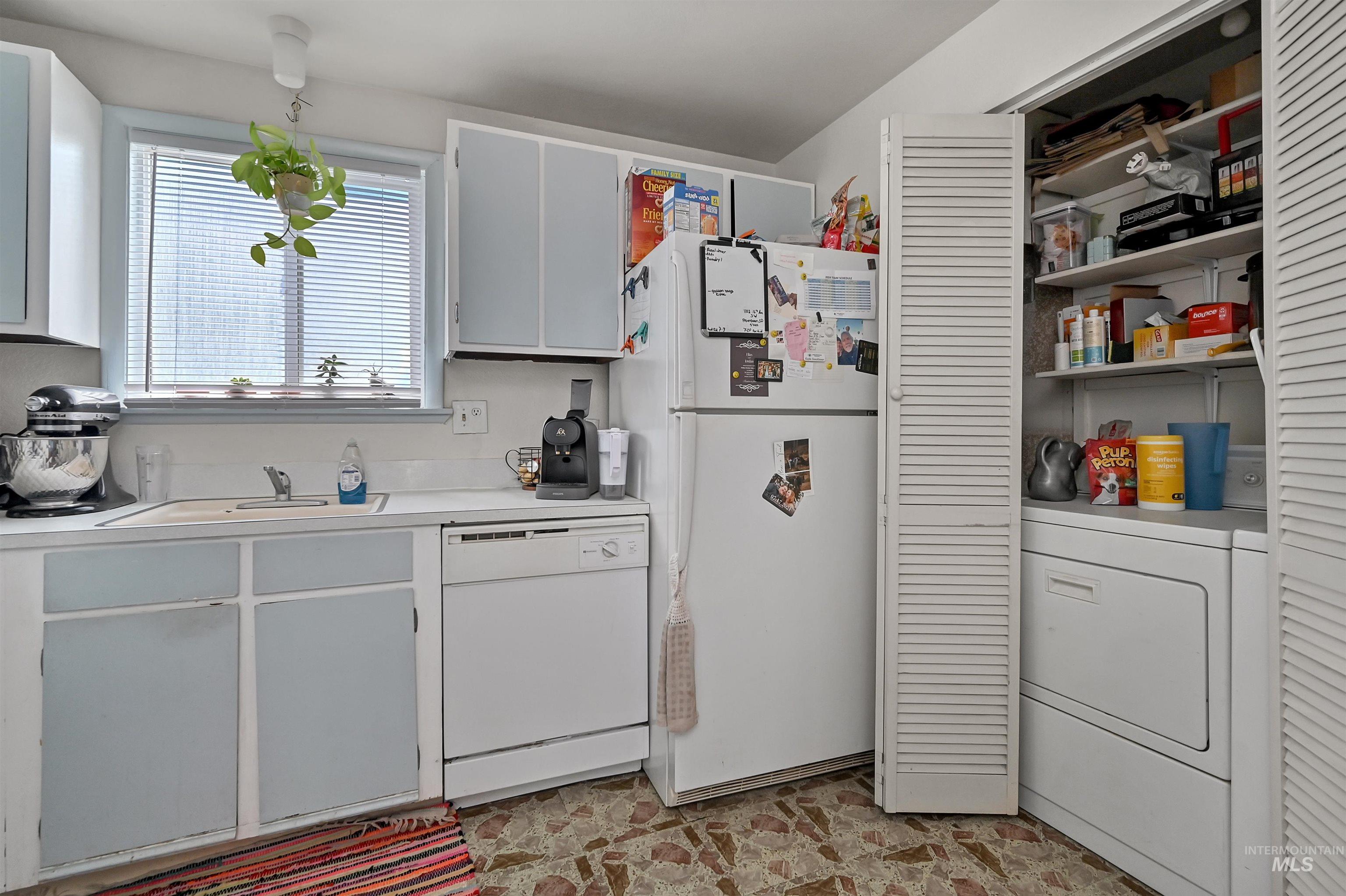Kitchen featuring white appliances, washer / dryer, light countertops, and white cabinetry