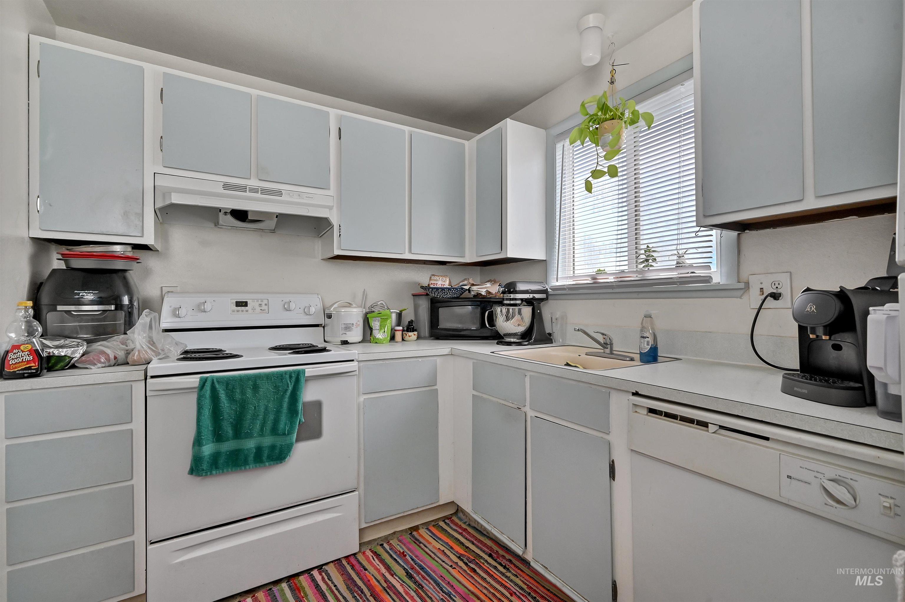 Kitchen featuring white appliances, light countertops, and under cabinet range hood