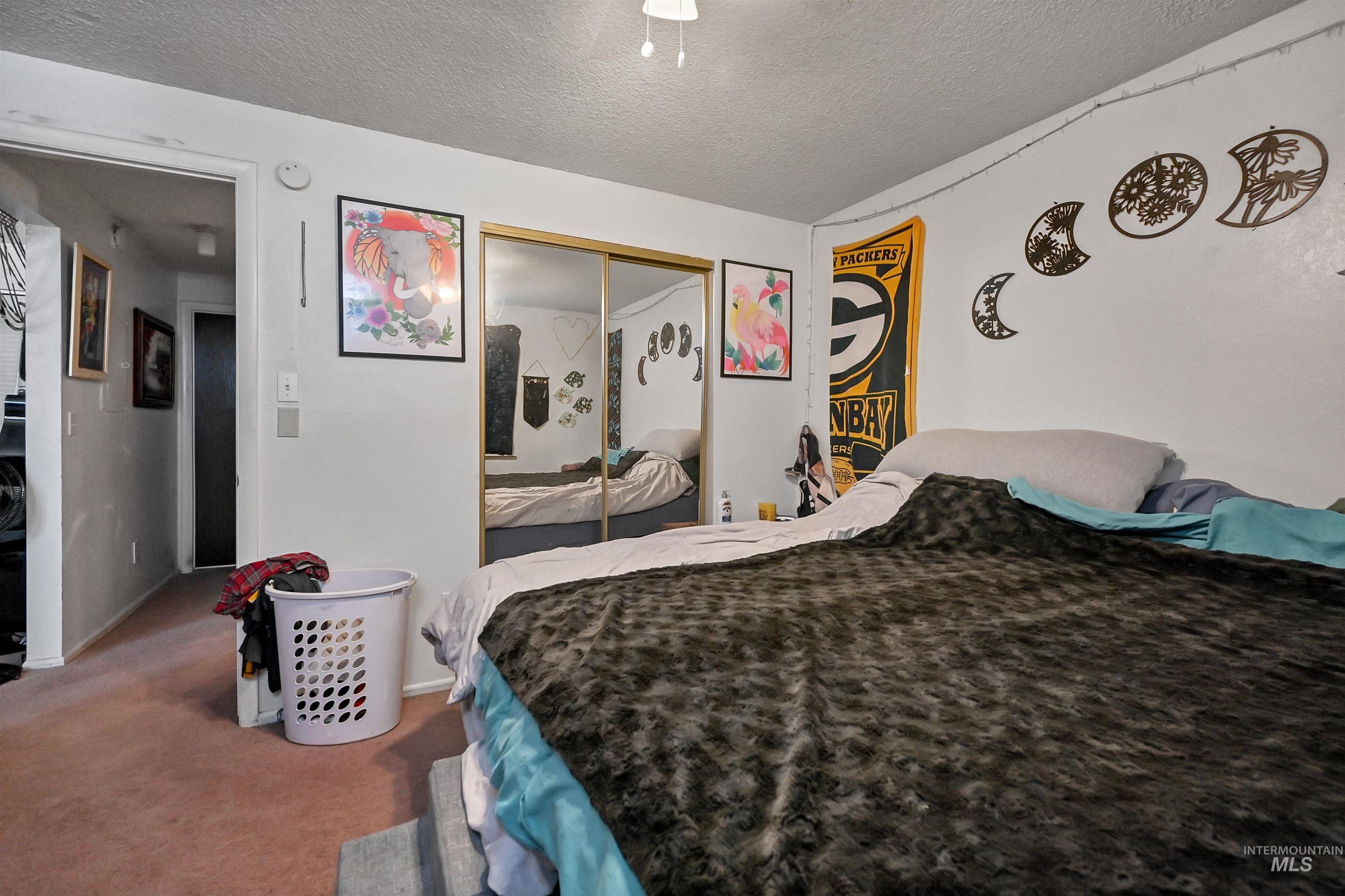 Carpeted bedroom featuring a textured ceiling, a closet, and ceiling fan