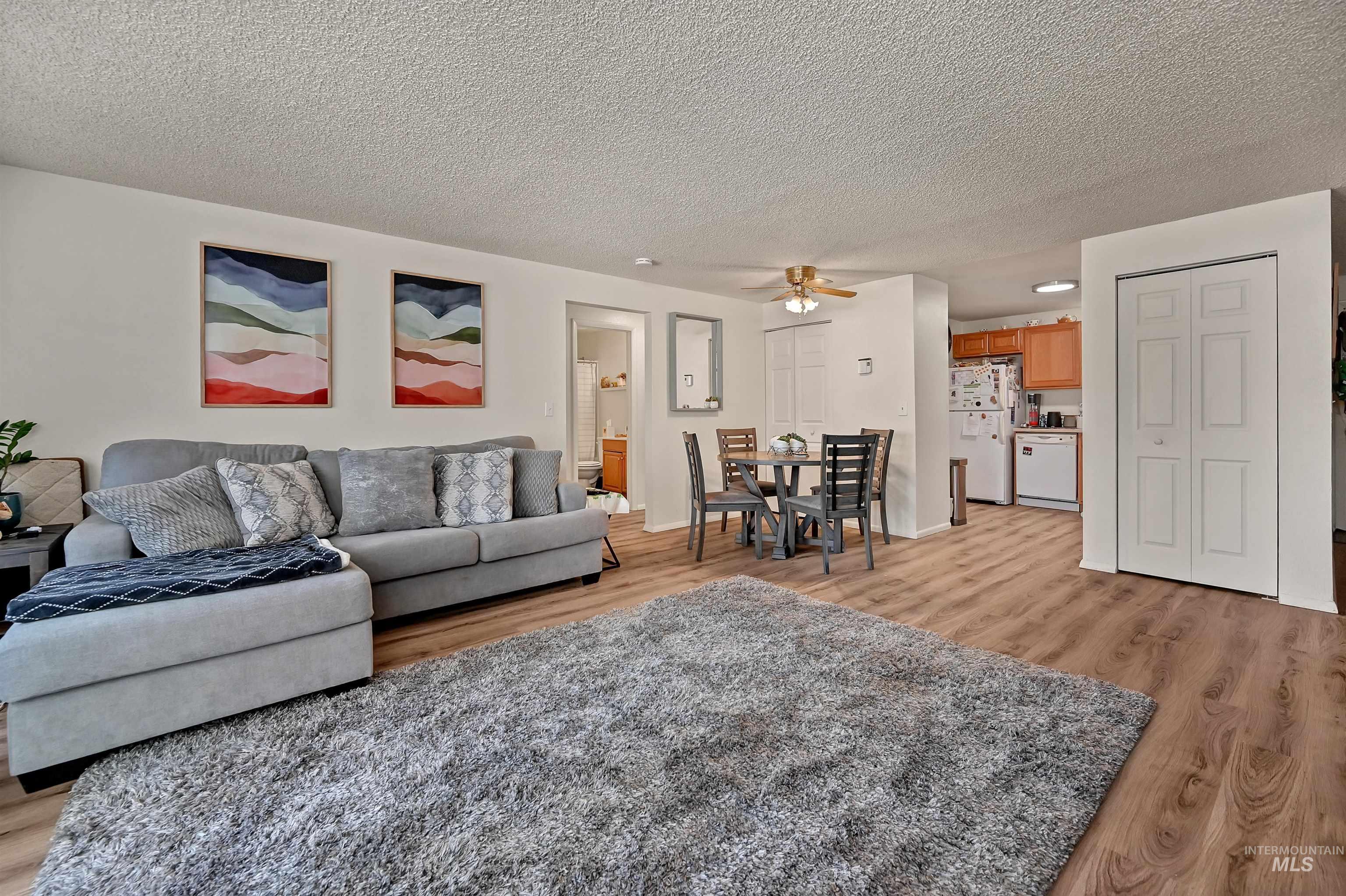 Living area with light wood-style floors, a textured ceiling, and a ceiling fan