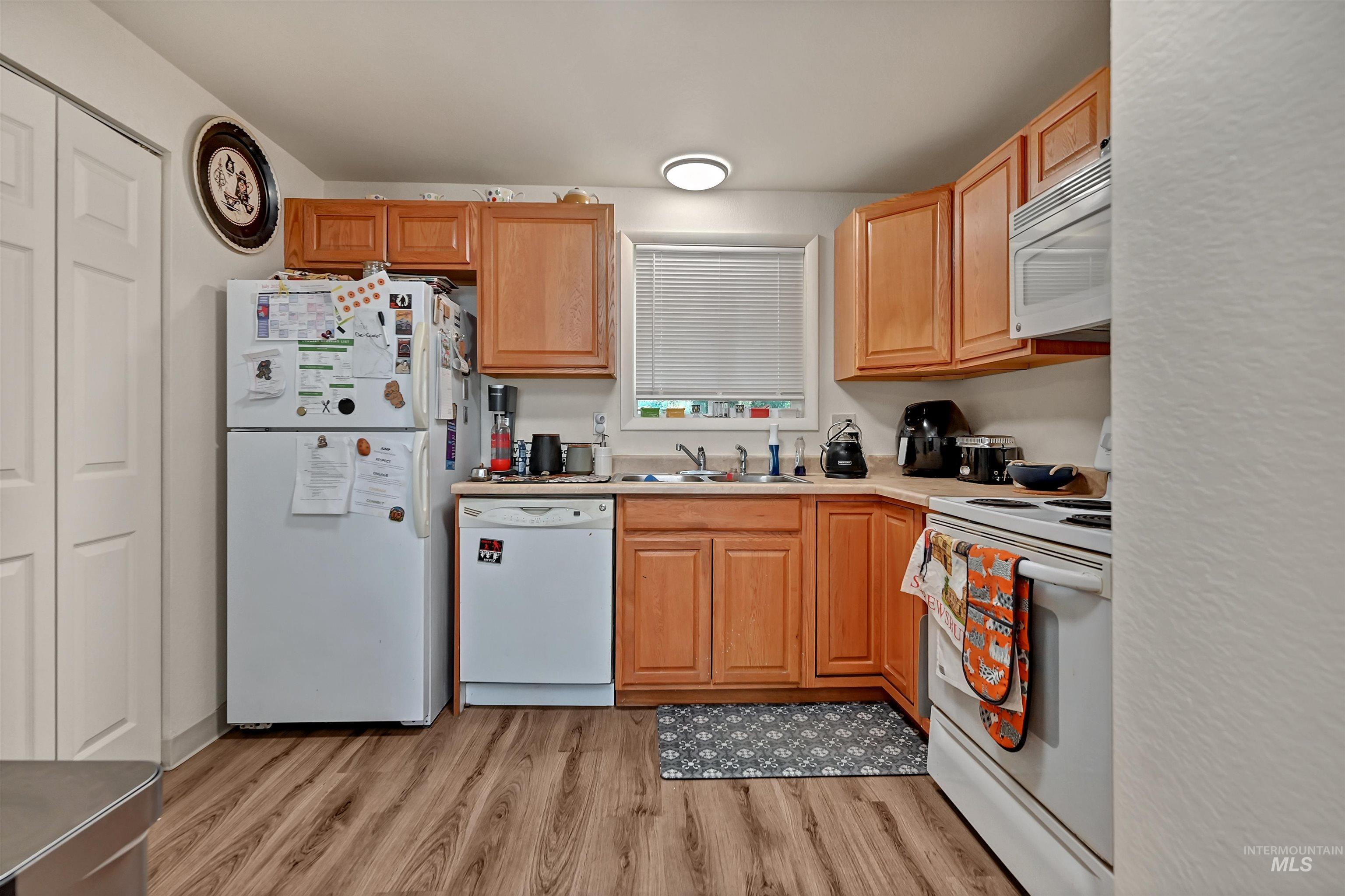 Kitchen featuring white appliances, light wood finished floors, and light countertops