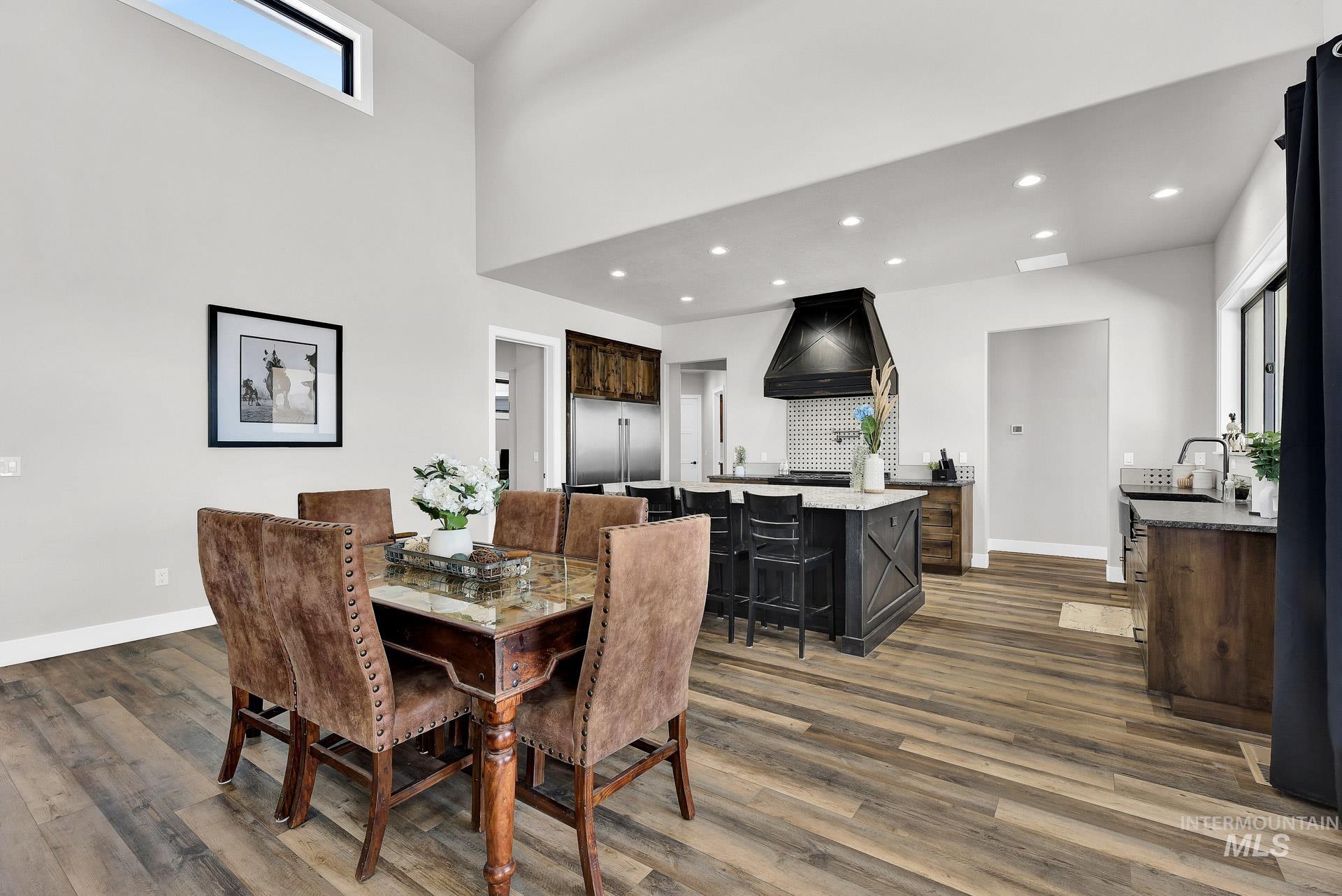Dining area featuring recessed lighting, dark wood-style floors, and a towering ceiling