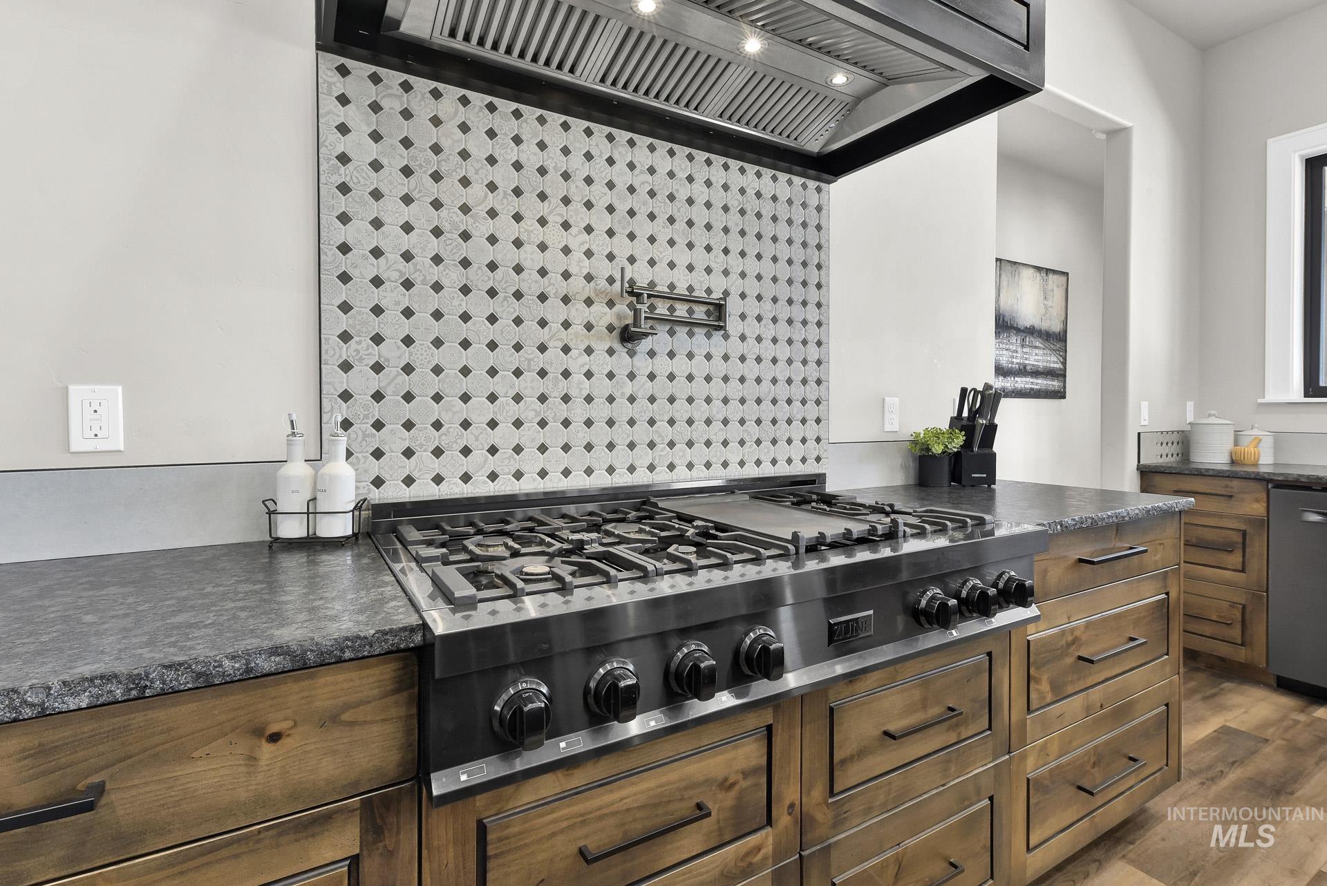 Kitchen featuring custom range hood, stainless steel appliances, dark countertops, and dark wood-style flooring