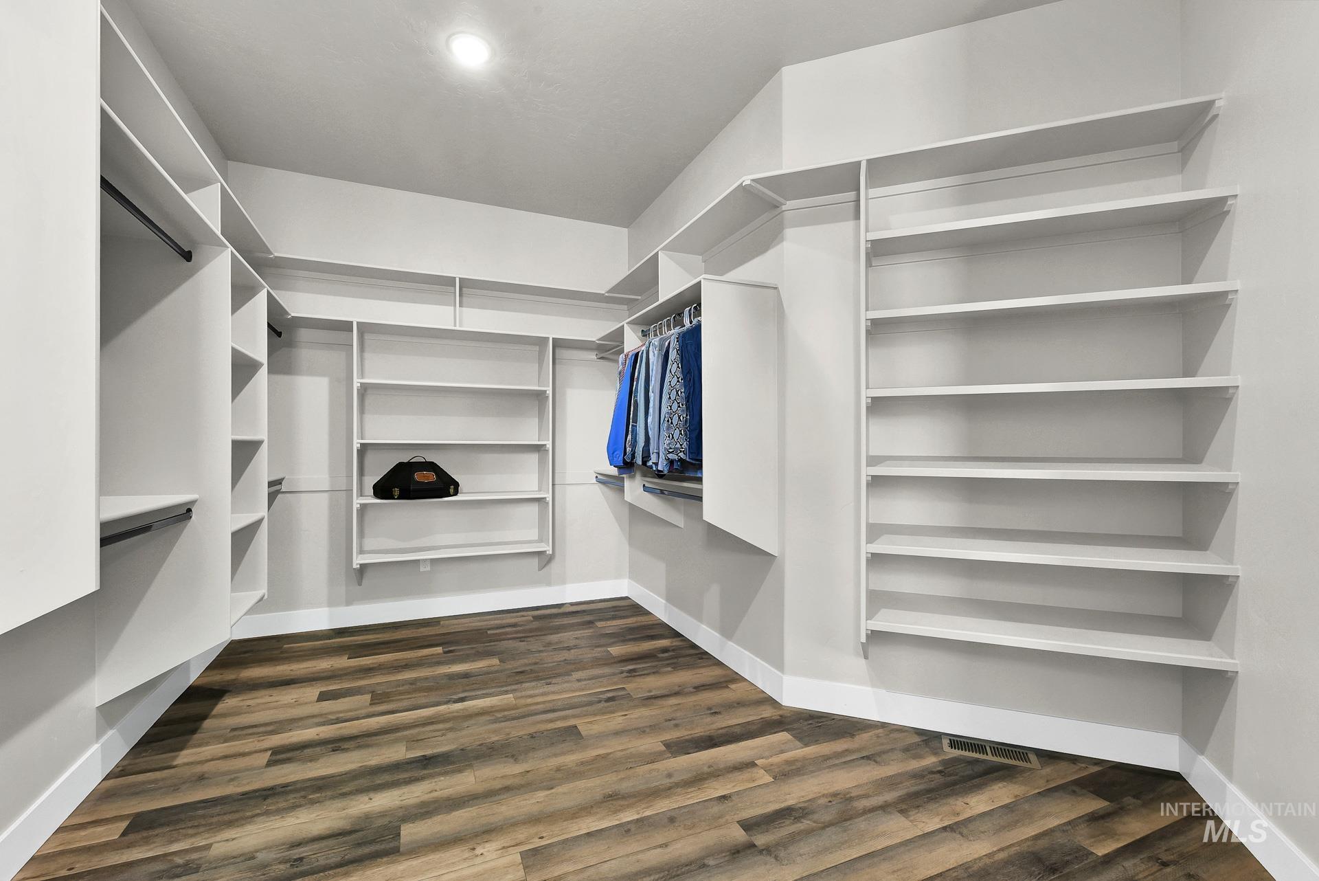 Walk in closet with dark wood-style flooring