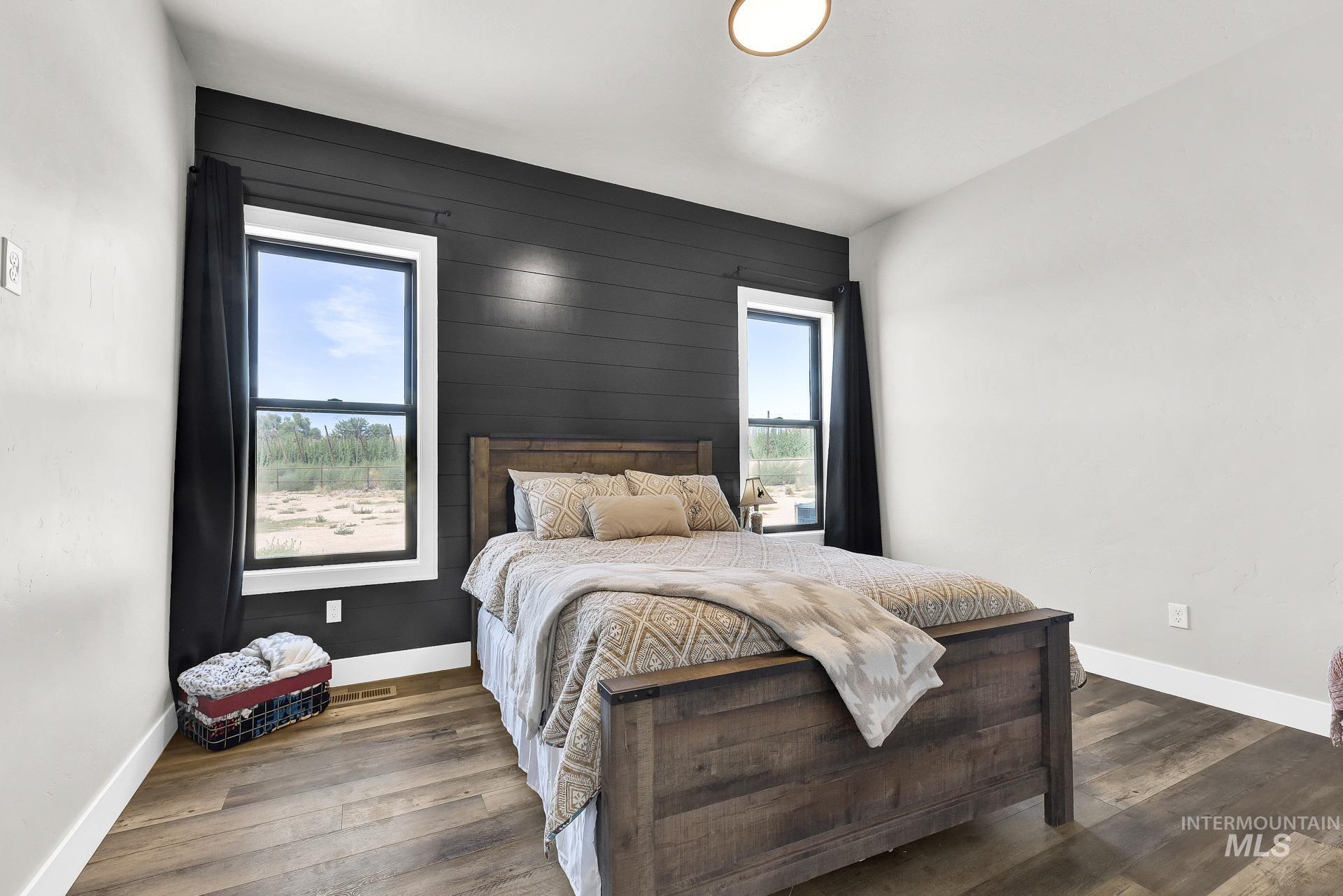 Bedroom with multiple windows, wood walls, and wood finished floors