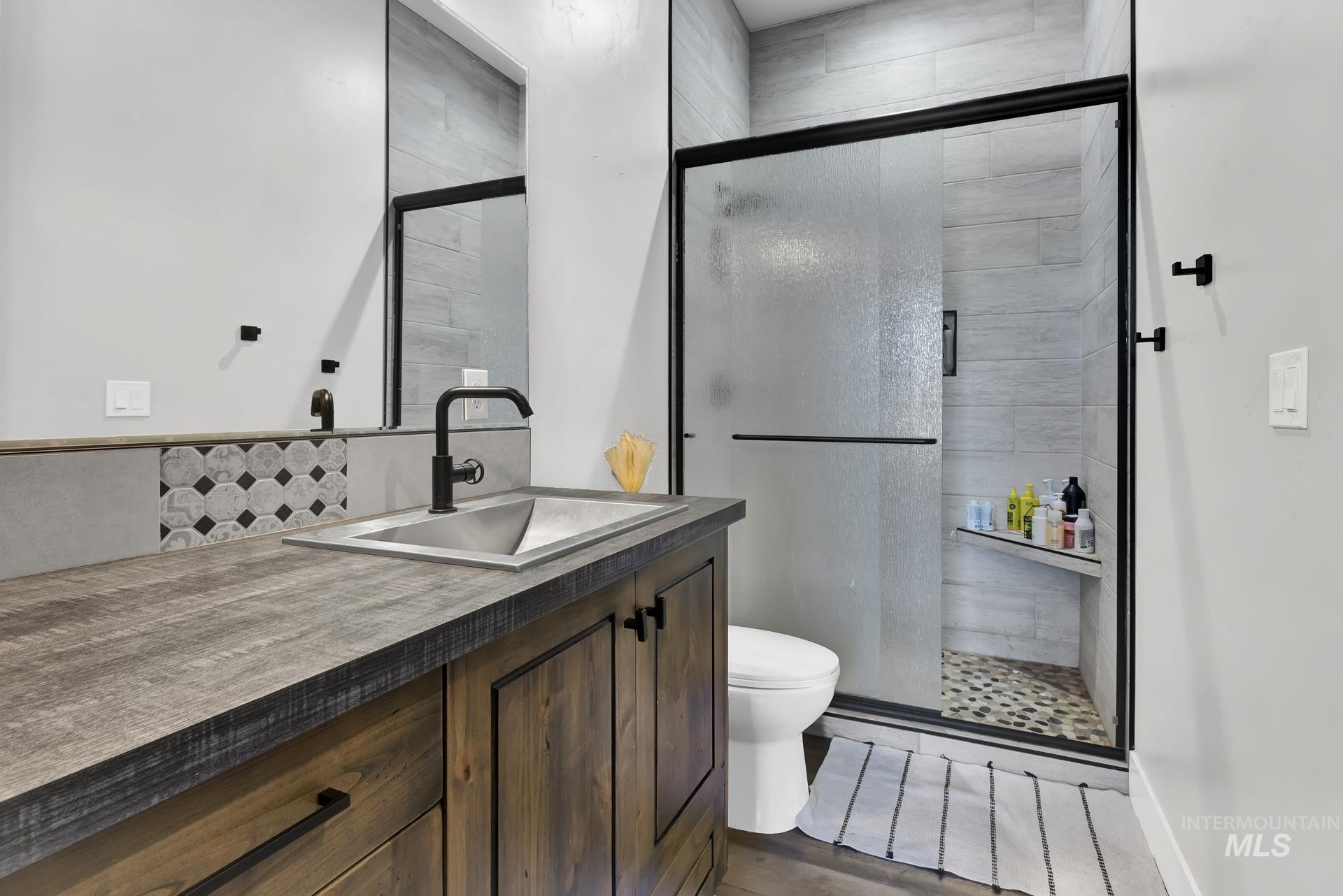 Full bathroom with vanity, a shower stall, and wood finished floors