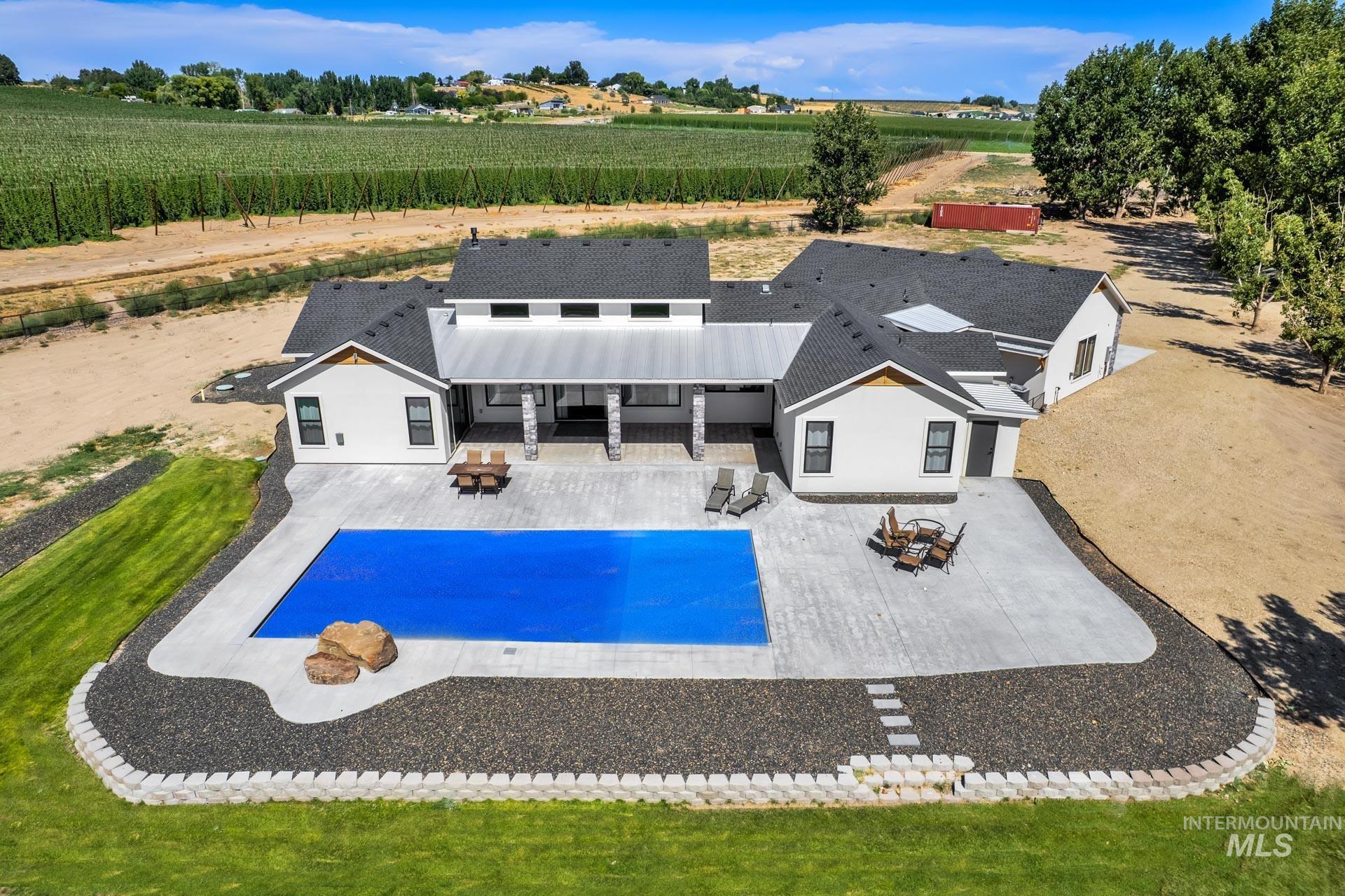 Swimming pool with a patio, a view of rural / pastoral area, and agricultural plots