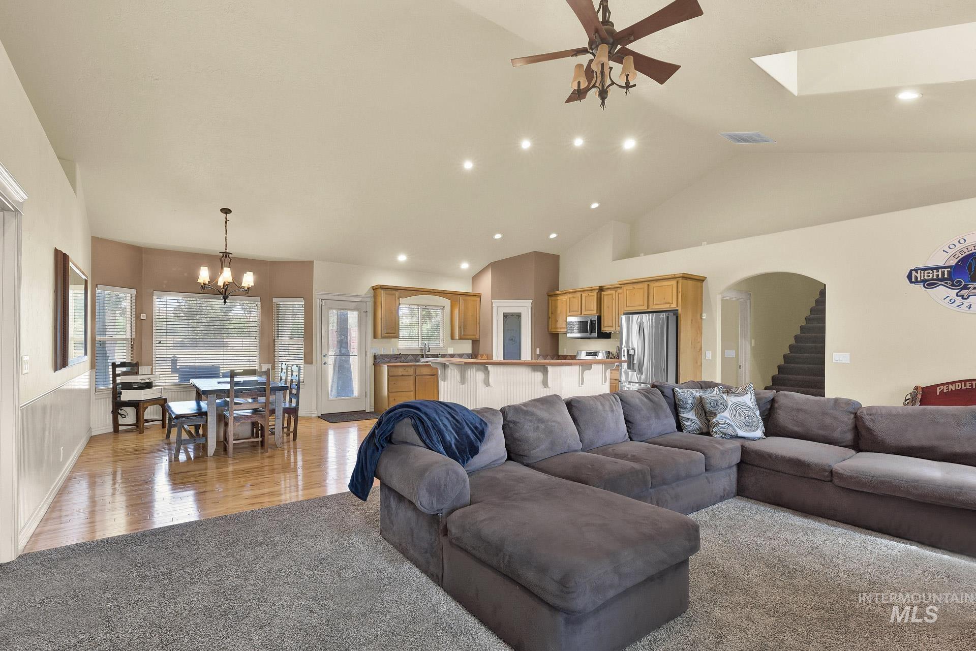 Living room with high vaulted ceiling, a chandelier, light colored carpet, recessed lighting, and a ceiling fan
