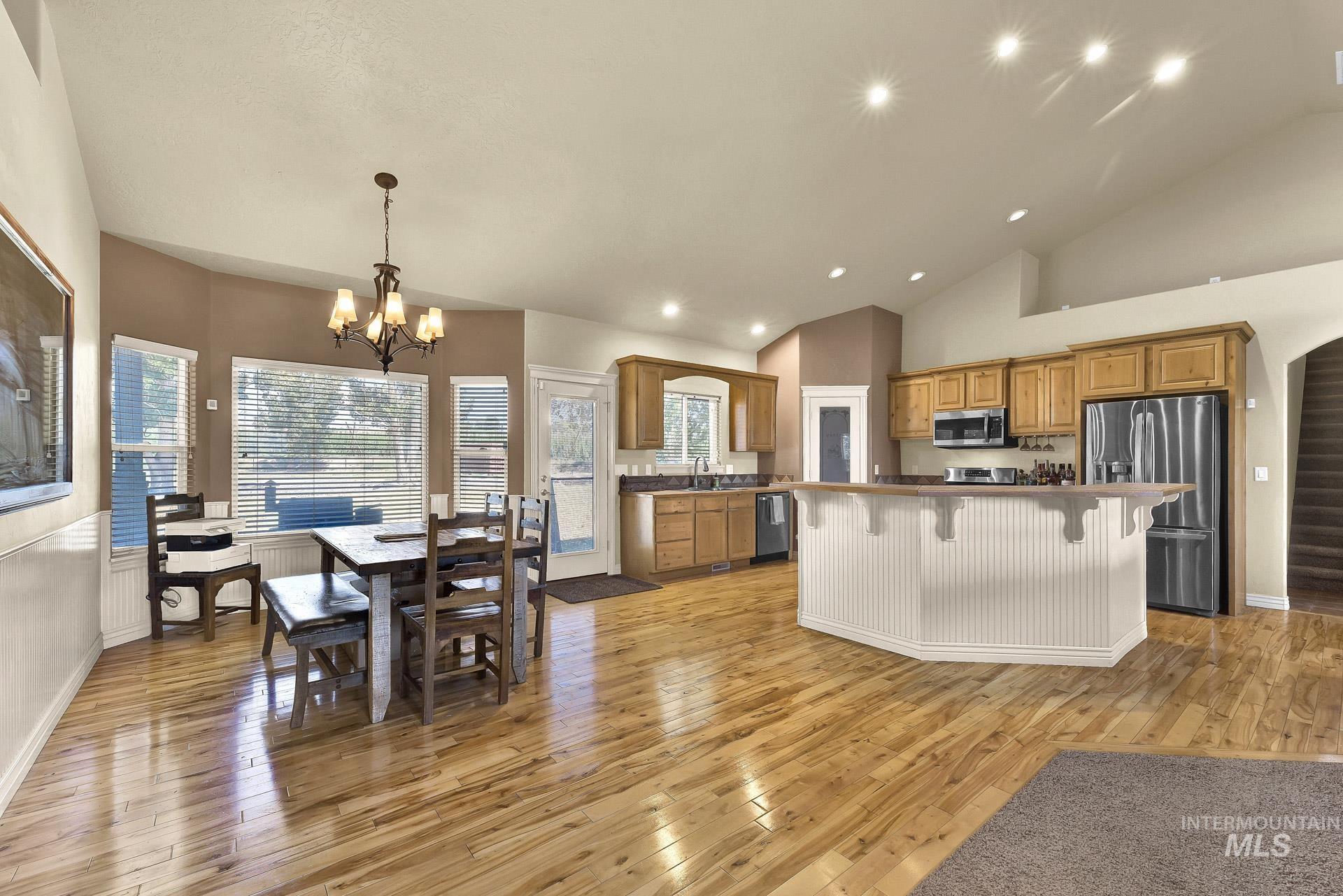 Kitchen with stainless steel appliances, light wood-style flooring, a kitchen breakfast bar, brown cabinets, and a kitchen island