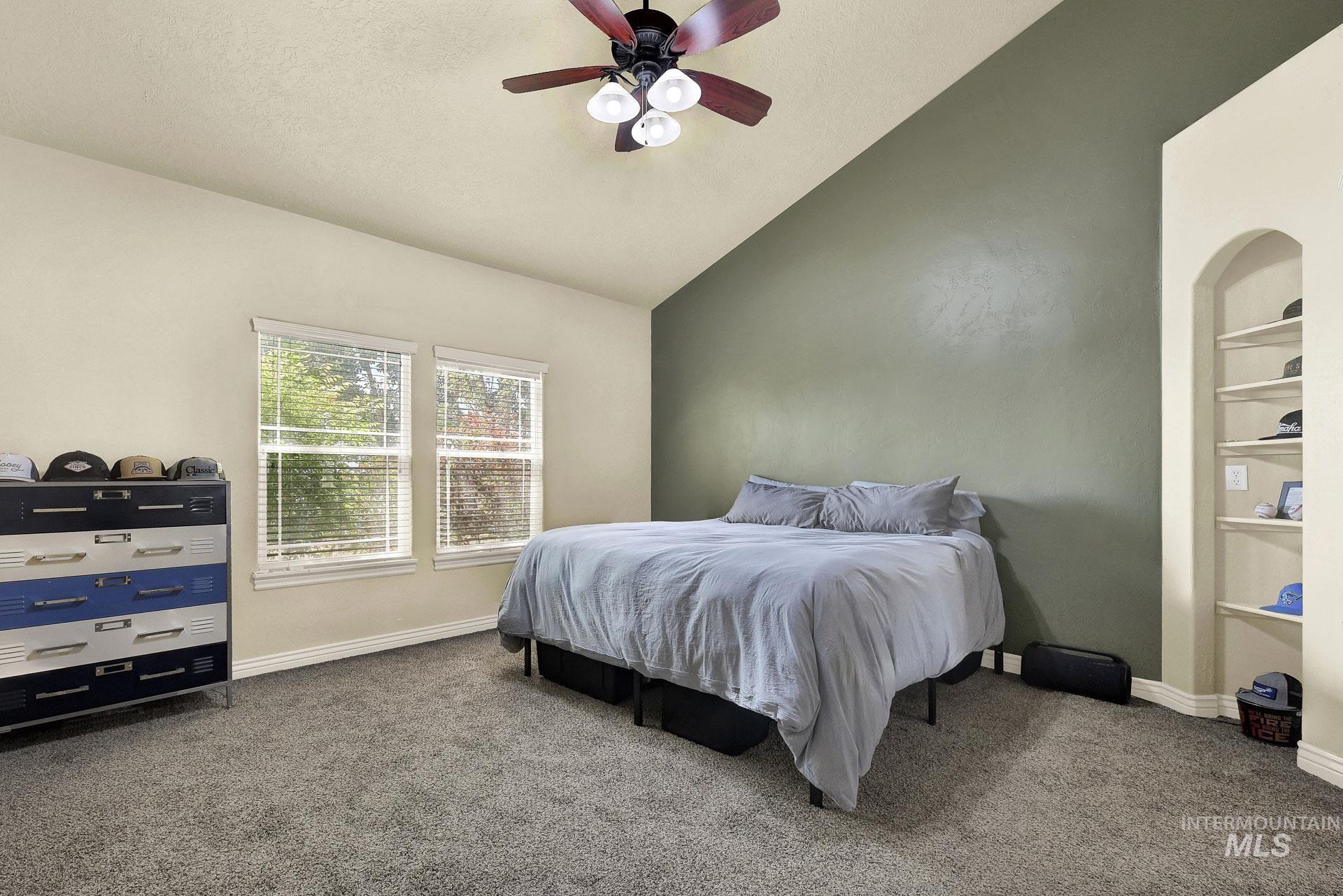 Carpeted bedroom with vaulted ceiling and a ceiling fan