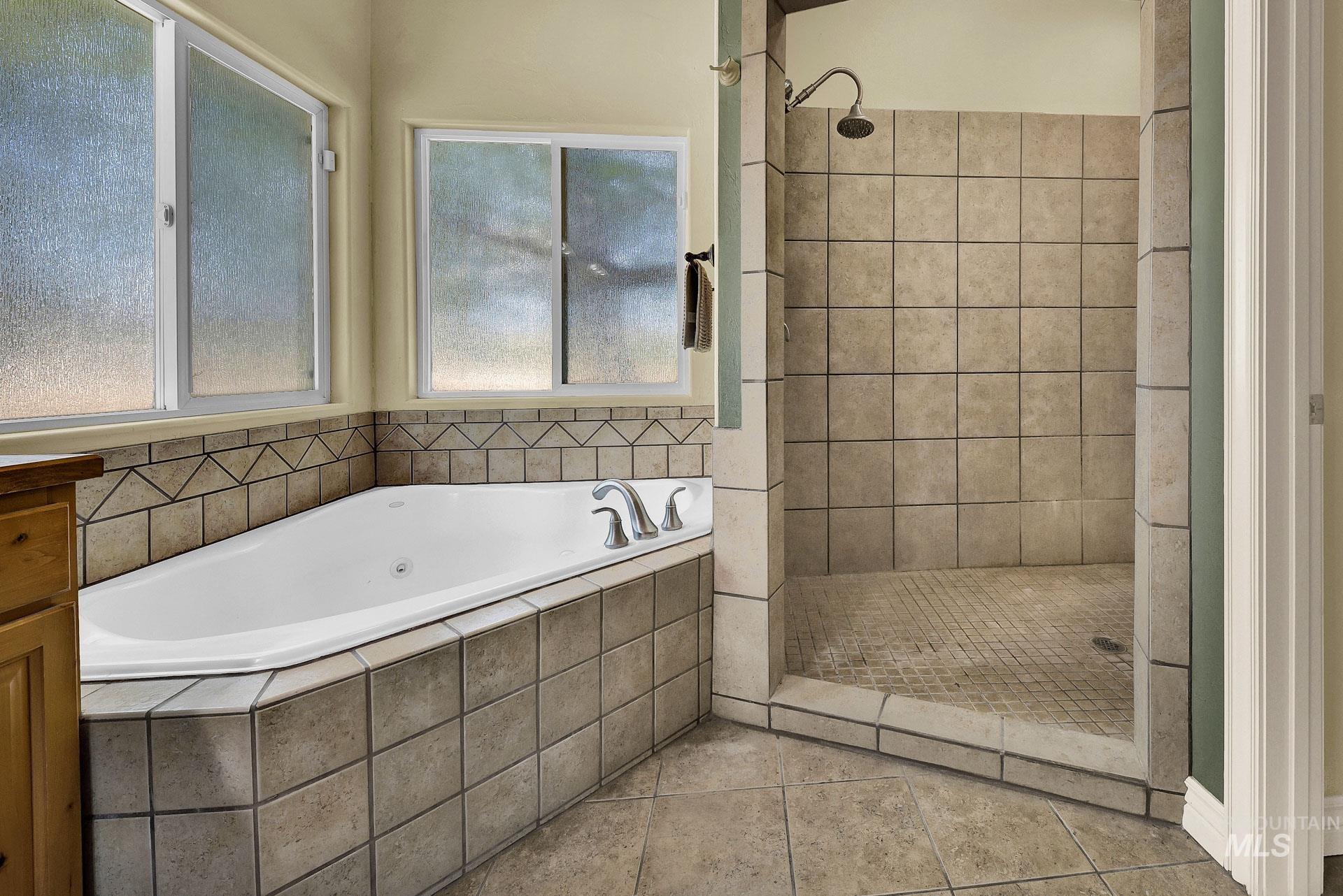Full bath featuring a garden tub, a tile shower, and tile patterned floors