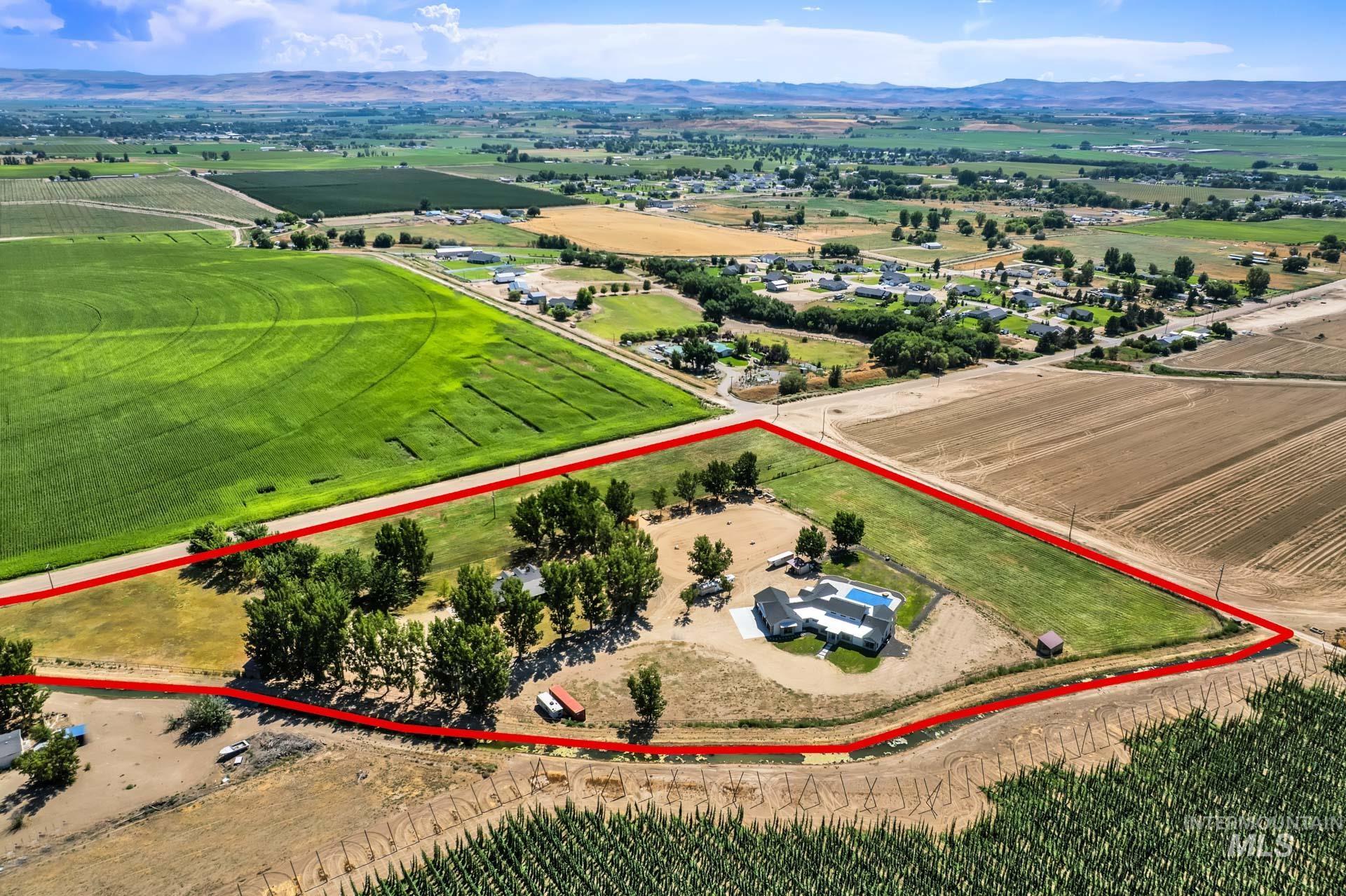 Overview of rural landscape with property parcel outlined, large plots for crops, and a mountainous background