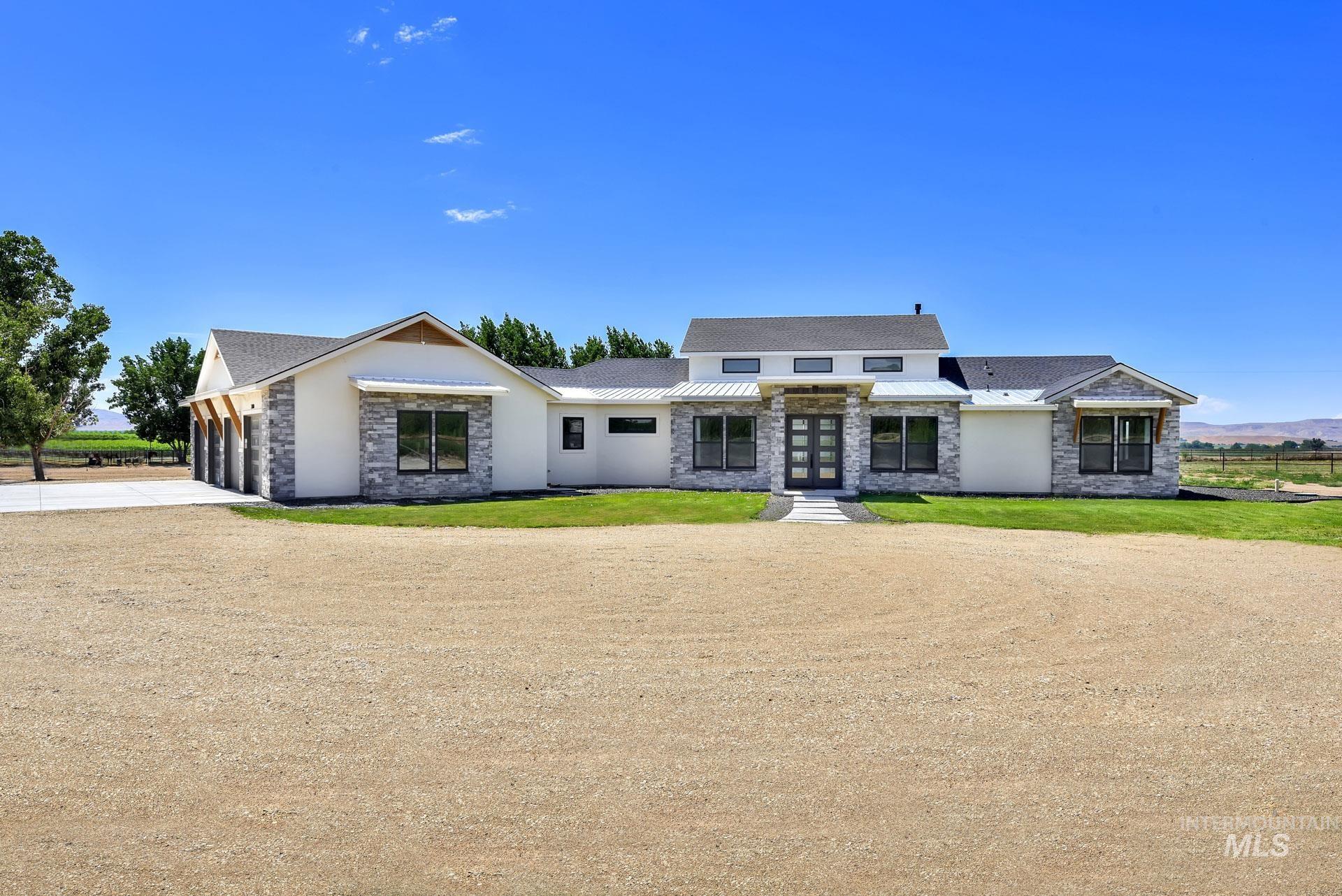 View of front of home featuring stone siding, driveway, a garage, and a front lawn