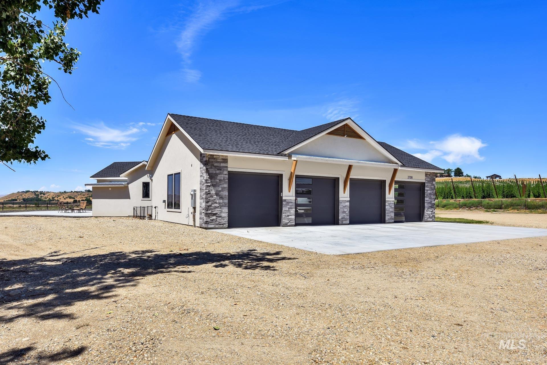 View of property exterior featuring driveway, stone siding, stucco siding, an attached garage, and roof with shingles