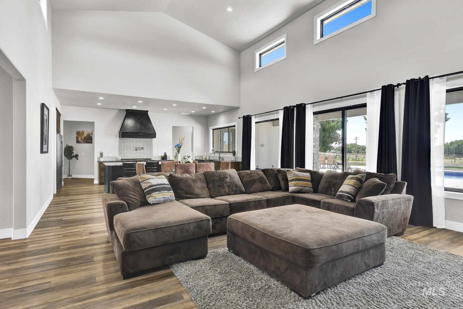 Living room with wood finished floors, high vaulted ceiling, and recessed lighting