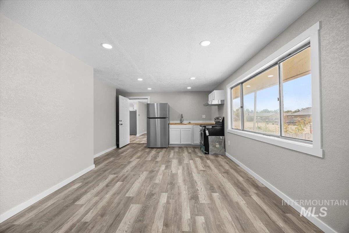 Unfurnished living room with a textured wall, light wood-style flooring, recessed lighting, and a textured ceiling