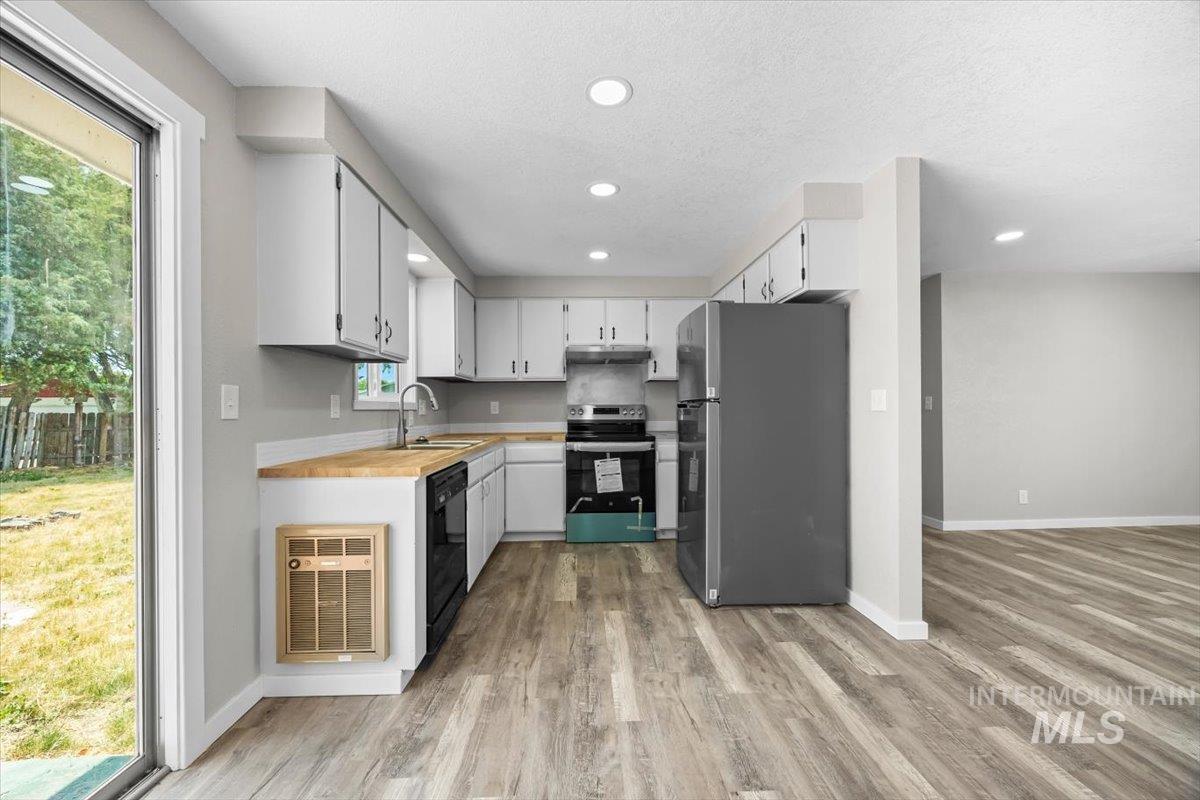 Kitchen featuring appliances with stainless steel finishes, light wood-style floors, recessed lighting, white cabinetry, and a textured ceiling