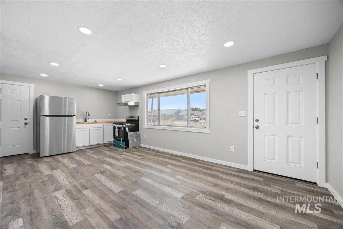 Unfurnished living room with recessed lighting, wood finished floors, and a textured ceiling